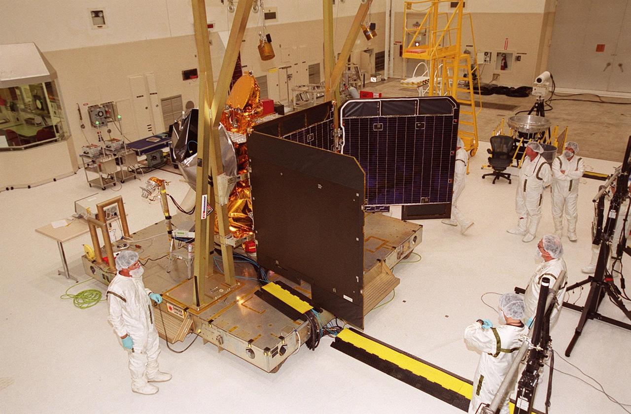 In the Spacecraft Assembly and Encapsulation Facility (SAEF 2), workers stand back as the panels of the solar array on the 2001 Mars Odyssey Orbiter open. The array will undergo illumination testing. Scheduled for launch April 7, 2001, the orbiter contains three science instruments: THEMIS, the Gamma Ray Spectrometer (GRS), and the Mars Radiation Environment Experiment (MARIE). THEMIS will map the mineralogy and morphology of the Martian surface using a high-resolution camera and a thermal infrared imaging spectrometer. The GRS will achieve global mapping of the elemental composition of the surface and determine the abundance of hydrogen in the shallow subsurface. The MARIE will characterize aspects of the near-space radiation environment with regards to the radiation-related risk to human explorers