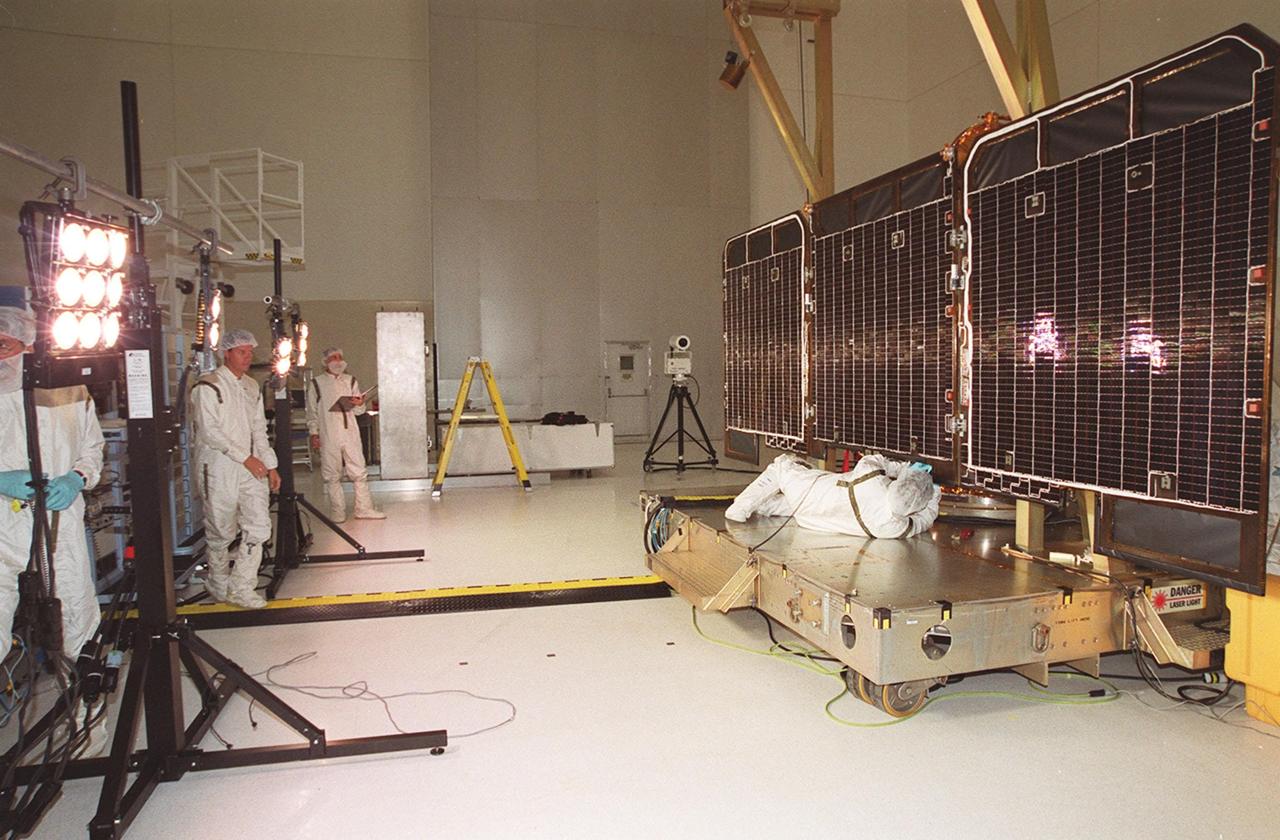 Arrays of lights (left) in the Spacecraft Assembly and Encapsulation Facility (SAEF 2) are used for illumination testing on the solar array panels at right. The panels are part of on the 2001 Mars Odyssey Orbiter. Scheduled for launch April 7, 2001, the orbiter contains three science instruments: THEMIS, the Gamma Ray Spectrometer (GRS), and the Mars Radiation Environment Experiment (MARIE). THEMIS will map the mineralogy and morphology of the Martian surface using a high-resolution camera and a thermal infrared imaging spectrometer. The GRS will achieve global mapping of the elemental composition of the surface and determine the abundance of hydrogen in the shallow subsurface. The MARIE will characterize aspects of the near-space radiation environment with regards to the radiation-related risk to human explorers