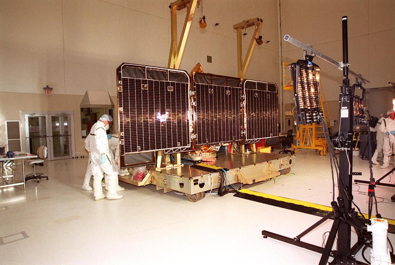 Solar array panels on the 2001 Mars Odyssey Orbiter undergo illumination testing in the Spacecraft Assembly and Encapsulation Facility (SAEF 2). Scheduled for launch April 7, 2001, the orbiter contains three science instruments: THEMIS, the Gamma Ray Spectrometer (GRS), and the Mars Radiation Environment Experiment (MARIE). THEMIS will map the mineralogy and morphology of the Martian surface using a high-resolution camera and a thermal infrared imaging spectrometer. The GRS will achieve global mapping of the elemental composition of the surface and determine the abundance of hydrogen in the shallow subsurface. The MARIE will characterize aspects of the near-space radiation environment with regards to the radiation-related risk to human explorers