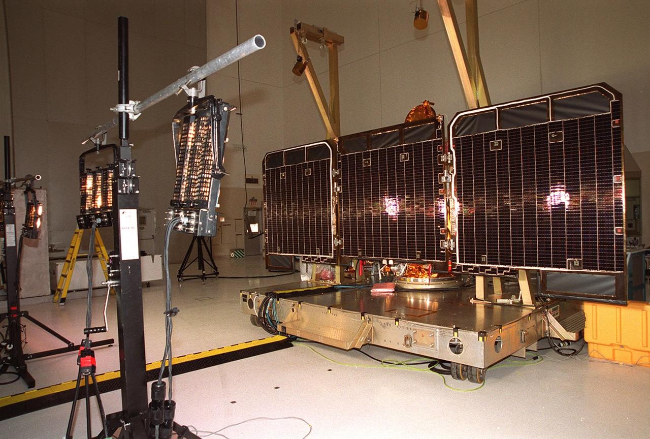 Arrays of lights at left focus on solar array panels at right during illumination testing. The solar array is part of the 2001 Mars Odyssey Orbiter. Scheduled for launch April 7, 2001, the orbiter contains three science instruments: THEMIS, the Gamma Ray Spectrometer (GRS), and the Mars Radiation Environment Experiment (MARIE). THEMIS will map the mineralogy and morphology of the Martian surface using a high-resolution camera and a thermal infrared imaging spectrometer. The GRS will achieve global mapping of the elemental composition of the surface and determine the abundance of hydrogen in the shallow subsurface. The MARIE will characterize aspects of the near-space radiation environment with regards to the radiation-related risk to human explorers