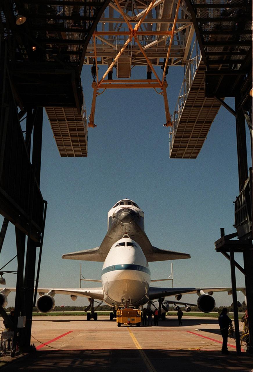 Viewed from behind the mate/demate device at the Shuttle Landing Facility, the Shuttle Carrier Aircraft and the orbiter Atlantis are towed toward the MDD where Atlantis will be lifted from the SCA. Atlantis landed in California Feb. 19 concluding mission STS-98. The ferry flight began in California March 1; unfavorable weather conditions kept it on the ground at Altus AFB, Okla., until it could return to Florida. The orbiter will next fly on mission STS-104, the 10th construction flight to the International Space Station, scheduled June 8