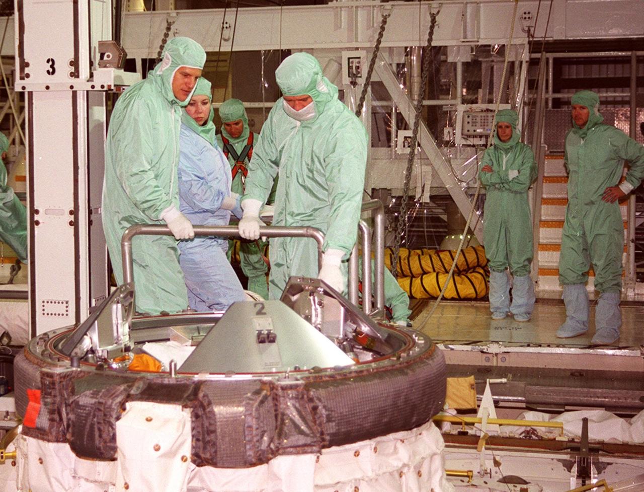 In the Orbiter Processing Facility bay 2, STS-100 Mission Specialist Scott Parazynski (left, foreground) and Chris Hadfield (right, foreground) look over the docking mechanism in payload bay of Endeavour. They are taking part in a Crew Equipment Interface Test (CEIT) along with other crew members Commander Kent V. Rominger, Pilot Jeffrey S. Ashby and Mission Specialists John L. Phillips, Umberto Guidoni, who is with the European Space Agency, and Yuri Lonchakov, who is with the Russian Aviation and Space Agency. Endeavour is also carrying the Multi-Purpose Logistics Module Raffaello to the International Space Station. Raffaello carries six system racks and two storage racks for the U.S. Lab. Launch of mission STS-100 is scheduled for April 19 at 2:41 p.m. EDT from Launch Pad 39A