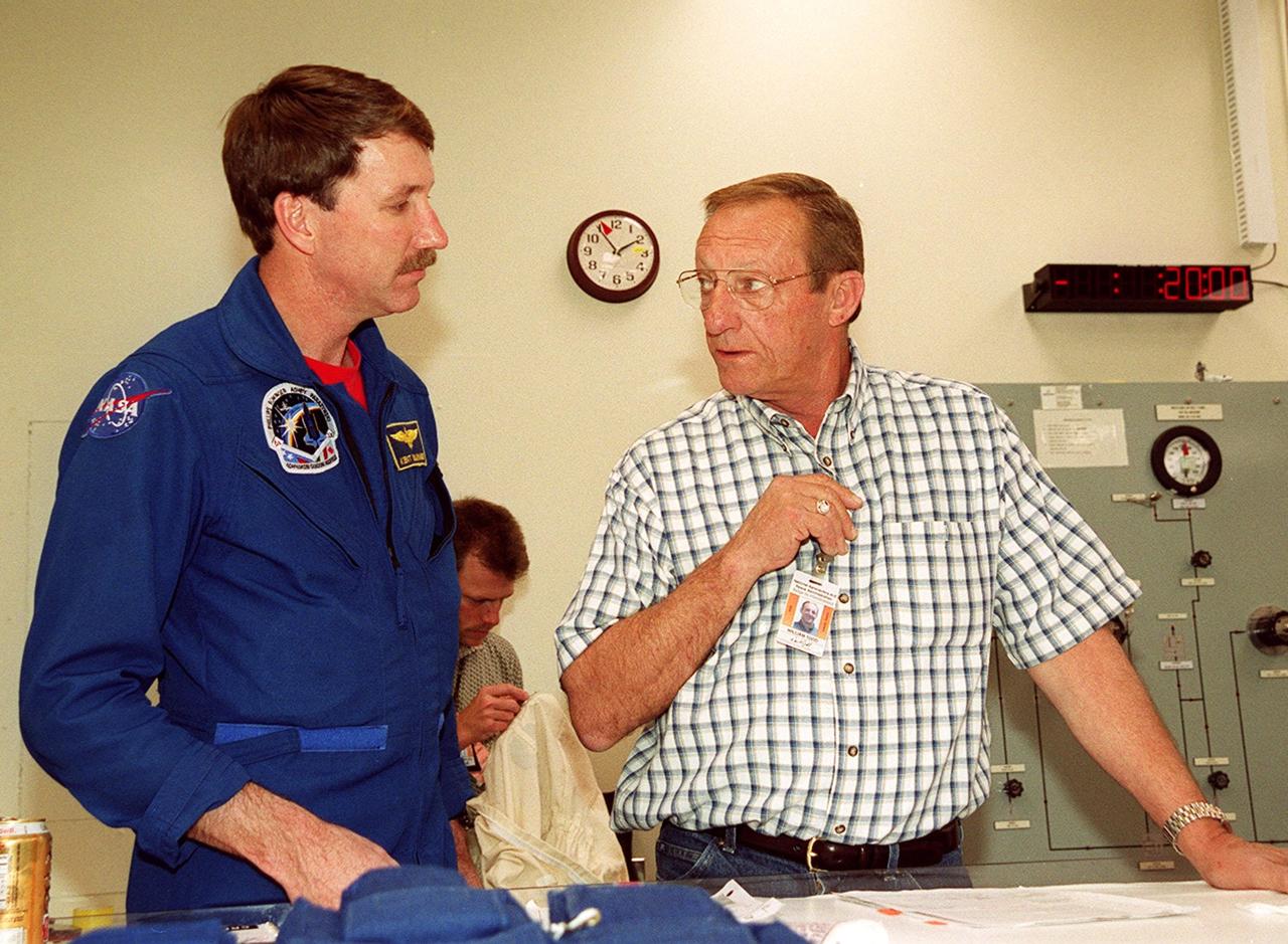 STS-100 Commander Kent V. Rominger (left) gets a review of equipment during suitup in the Operations and Checkout Building. He and the rest of the crew Pilot Jeff Ashby and Mission Specialists Chris Hadfield, Scott E. Parazynski, John L. Phillips, Umberto Guidoni and Yuri Lonchakov are taking part in Terminal Countdown Demonstration Test activities, from emergency escape training at the pad to a simulated launch countdown. An international crew, Hadfield is with the Canadian Space Agency, Guidoni the European Space Agency and Lonchakov the Russian Aviation and Space Agency. The mission is carrying the Multi-Purpose Logistics Module Raffaello and the Canadian robotic arm, SSRMS, to the International Space Station. Raffaello carries six system racks and two storage racks for the U.S. Lab. The SSRMS is crucial to the continued assembly of the orbiting complex and has a unique ability to switch ends as it works, “inchworming” along the Station’s exterior. Launch of mission STS-100 is scheduled for April 19 at 2:41 p.m. EDT from Launch Pad 39A