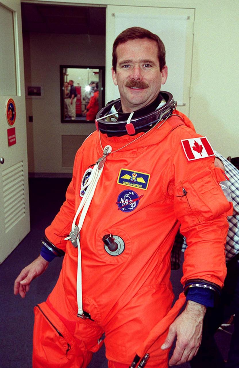 STS-100 Mission Specialist Chris Hadfield smiles for the camera during suitup in the Operations and Checkout Building. He and the rest of the crew Commander Kent V. Rominger, Pilot Jeffrey S. Ashby and Mission Specialists Scott E. Parazynski, John L. Phillips, Umberto Guidoni and Yuri Lonchakov are taking part in Terminal Countdown Demonstration Test activities, from emergency escape training at the pad to a simulated launch countdown. An international crew, Hadfield is with the Canadian Space Agency, Guidoni the European Space Agency and Lonchakov the Russian Aviation and Space Agency. The mission is carrying the Multi-Purpose Logistics Module Raffaello and the Canadian robotic arm, SSRMS, to the International Space Station. Raffaello carries six system racks and two storage racks for the U.S. Lab. The SSRMS is crucial to the continued assembly of the orbiting complex and has a unique ability to switch ends as it works, “inchworming” along the Station’s exterior. Launch of mission STS-100 is scheduled for April 19 at 2:41 p.m. EDT from Launch Pad 39A