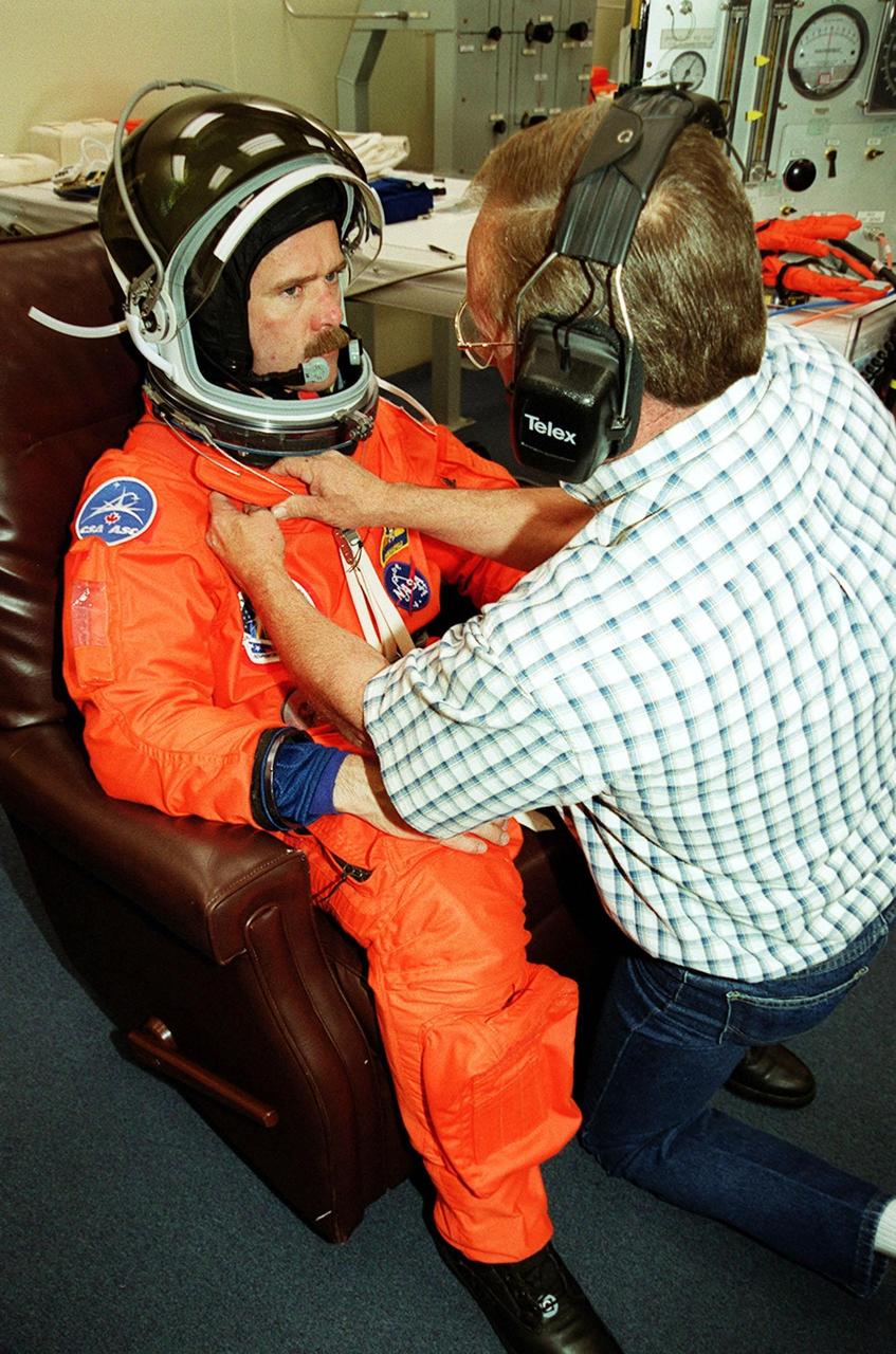 In the Operations and Checkout Building, STS-100 Mission Specialist Chris Hadfield gets his launch suit adjusted by a suit technician. Hadfield and the rest of the crew Commander Kent V. Rominger, Pilot Jeffrey S. Ashby and Mission Specialists Scott E. Parazynski, John L. Phillips, Umberto Guidoni and Yuri Lonchakov are taking part in Terminal Countdown Demonstration Test activities, from emergency escape training at the pad to a simulated launch countdown. An international crew, Hadfield is with the Canadian Space Agency, Guidoni the European Space Agency and Lonchakov the Russian Aviation and Space Agency. The mission is carrying the Multi-Purpose Logistics Module Raffaello and the Canadian robotic arm, SSRMS, to the International Space Station. Raffaello carries six system racks and two storage racks for the U.S. Lab. The SSRMS is crucial to the continued assembly of the orbiting complex and has a unique ability to switch ends as it works, “inchworming” along the Station’s exterior. Launch of mission STS-100 is scheduled for April 19 at 2:41 p.m. EDT from Launch Pad 39A