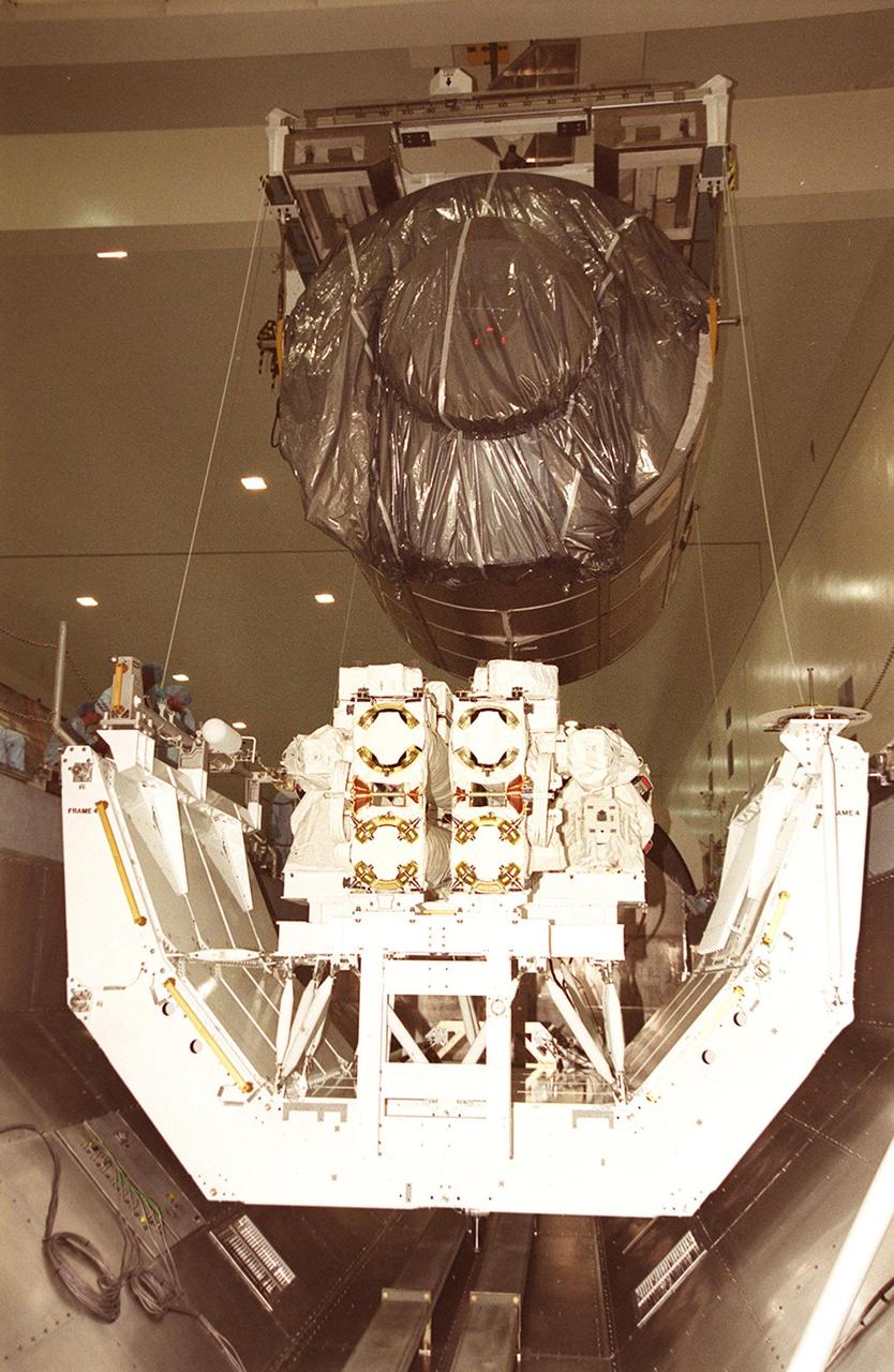 Viewed from the end, the Multi-Purpose Logistics Module Raffaello is lowered into the payload canister behind the Canadian robotic arm, SSRMS, already in place. Both elements are part of the payload on mission STS-100 to the International Space Station. Raffaello carries six system racks and two storage racks for the U.S. Lab. The arm has seven motorized joints and is capable of handling large payloads and assisting with docking the Space Shuttle. The SSRMS is self-relocatable with a Latching End Effector so it can be attached to complementary ports spread throughout the Station’s exterior surfaces. Launch of STS-100 is scheduled for April 19, 2001 at 2:41 p.m. EDT from Launch Pad 39A