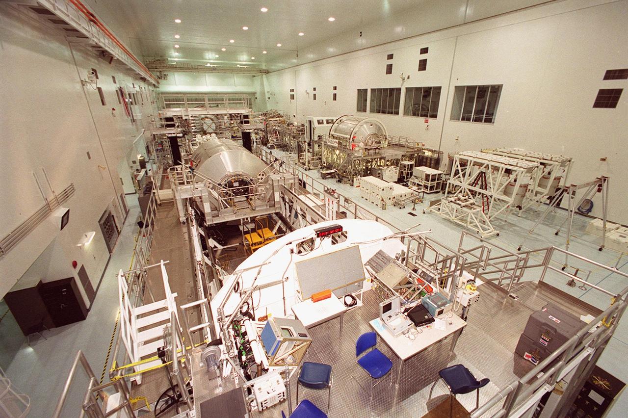 An overview of the Space Station Processing Facility shows equipment and future payloads on Shuttle missions to the International Space Station. At left is a Multi-Purpose Logistics Module Raffaello; at right another MPLM, Donatello. Windows on the wall at right give visitors on bus tours a look at operations during the day