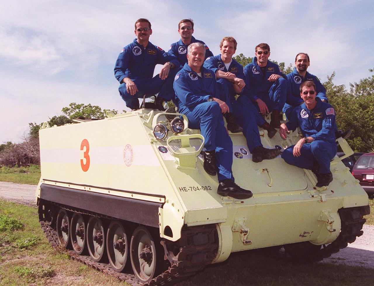 Before beginning training on the M-113 armored carrier they are sitting on, the STS-100 crew pauses for a group photo. Seen, from left, are Mission Specialists Chris A. Hadfield, Yuri V. Lonchakov, John L. Phillips, and Scott E. Parazynski; Pilot Jeffrey S. Ashby; Mission Specialist Umberto guidoni; and Commander Kent V. Rominger. They are taking part in Terminal Countdown Demonstration Test activities, which include emergency escape training, payload walkdown and a simulated launch countdown. The primary payload on mission STS-100 comprises the Canadian robotic arm, SSRMS, and Multi-Purpose Logistics Module, Raffaello. Launch of Space Shuttle Endeavour on mission STS-100 is targeted for April 19 at 2:41 p.m. EDT from Launch Pad 39A