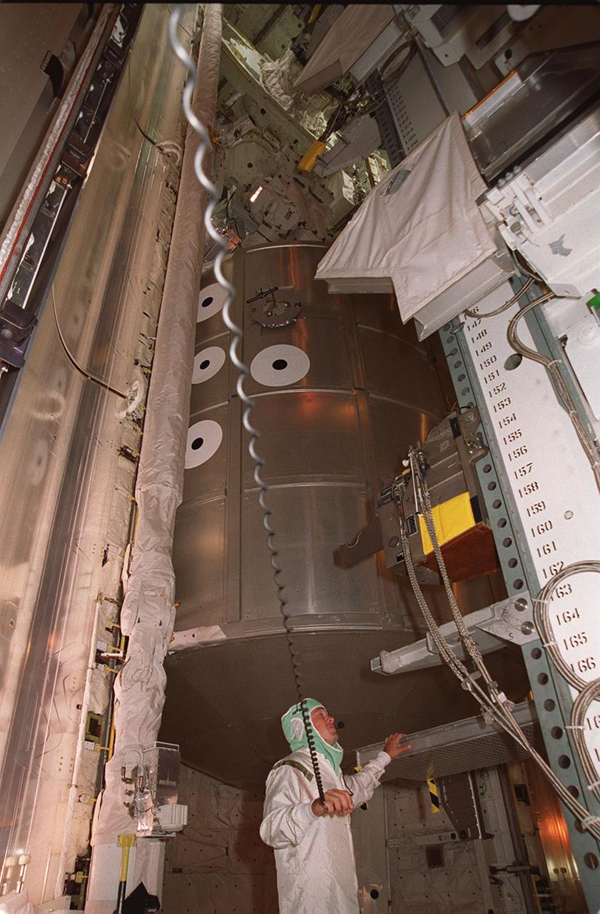 A worker in the Payload Changeout Room, Launch Pad 39A, moves the Payload Ground Handling Mechanism away from the open doors of Space Shuttle Endeavour’s payload bay. The PGHM helped move the STS-100 mission payload into the bay. Visible above and behind the worker is the Multi-Purpose Logistics Module Raffaello, which carries six system racks and two storage racks for the U.S. Lab. Above Raffaello is the Canadian robotic arm, the SSRMS. Capable of handling large payloads and assisting with docking the Space Shuttle, the SSRMS is crucial to the continued assembly of the International Space Station. Launch of mission STS-100 is scheduled for April 19 at 2:41 p.m. EDT