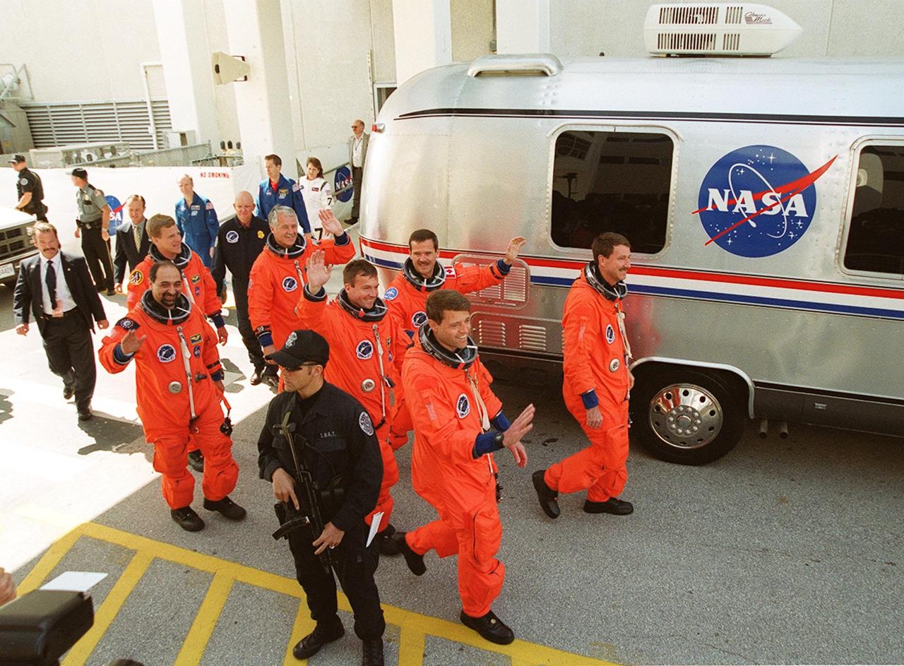 Leaving the Operations and Checkout Building, the STS-100 crew waves to well-wishers and heads to the Astrovan for transport to Launch Pad 39A. . Leading in front are Pilot Jeffrey S. Ashby (left) and Commander Kent V. Rominger (right). Behind them are (left to right) Mission Specialists Yuri Lonchakov and Chris A. Hadfield. Next are Mission Specialists Umberto Guidoni (left) and John L. Phillips (right). Following in the rear is Mission Specialist Scott E. Parazynski. An international crew, Guidoni represents the European Space Agency, Lonchakov the Russian Aviation and Space Agency and Hadfield the Canadian Space Agency. Space Shuttle Endeavour and its crew will deliver and integrate the Spacelab Logistics Pallet/Launch Deployment Assembly, which includes the Space Station Remote Manipulator System and the UHF Antenna. The mission includes two planned spacewalks for installation of the SSRMS, which will be performed by Parazynski and Hadfield. The mission is also the inaugural flight of Multi-Purpose Logistics Module Raffaello, carrying resupply stowage racks and resupply/return stowage platforms. Liftoff of Space Shuttle Endeavour on mission STS-100 is scheduled at 2:41 p.m. EDT April 19