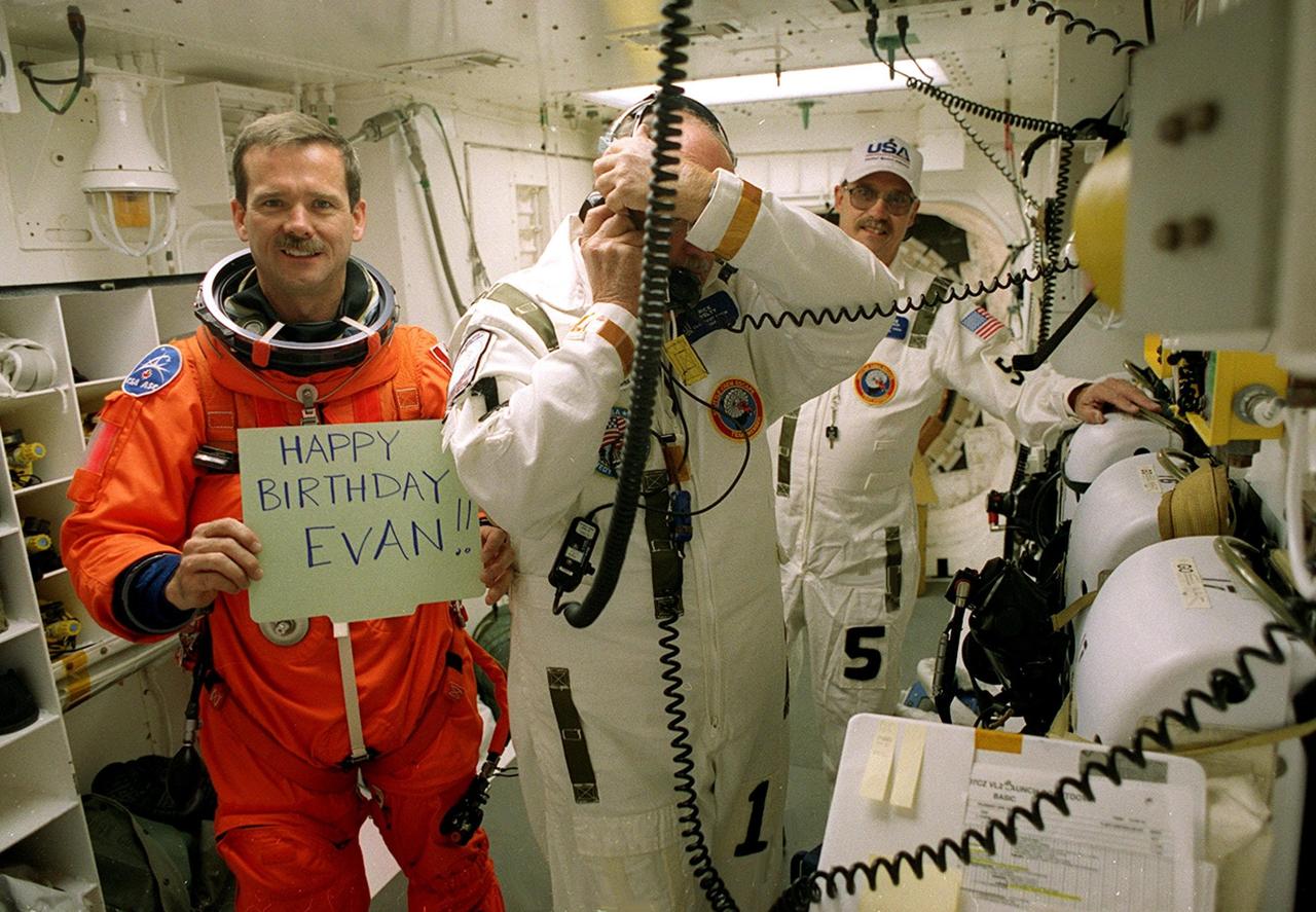 In the White Room, STS-100 Mission Specialist Chris A. Hadfield displays a special sign to a family member before entering Space Shuttle Endeavour. Closeout crew members Rick Welty (front) and George Schramm (behind) are available to help with Hadfield’s launch and entry suit. The White Room is an environmental chamber at the end of the Orbiter Access Arm that provides entry into the orbiter on the launch pad. The mission will deliver and integrate the Spacelab Logistics Pallet/Launch Deployment Assembly, which includes the Canadian-built Space Station Remote Manipulator System and the UHF Antenna. Two spacewalks are planned for installation of the SSRMS, which will be performed by Mission Specialist Scott E. Parazynski and. Hadfield, who is with the Canadian Space Agency. The mission is also the inaugural flight of Multi-Purpose Logistics Module Raffaello, carrying resupply stowage racks and resupply/return stowage platforms. Liftoff of Space Shuttle Endeavour on mission STS-100 is scheduled at 2:41 p.m. EDT April 19