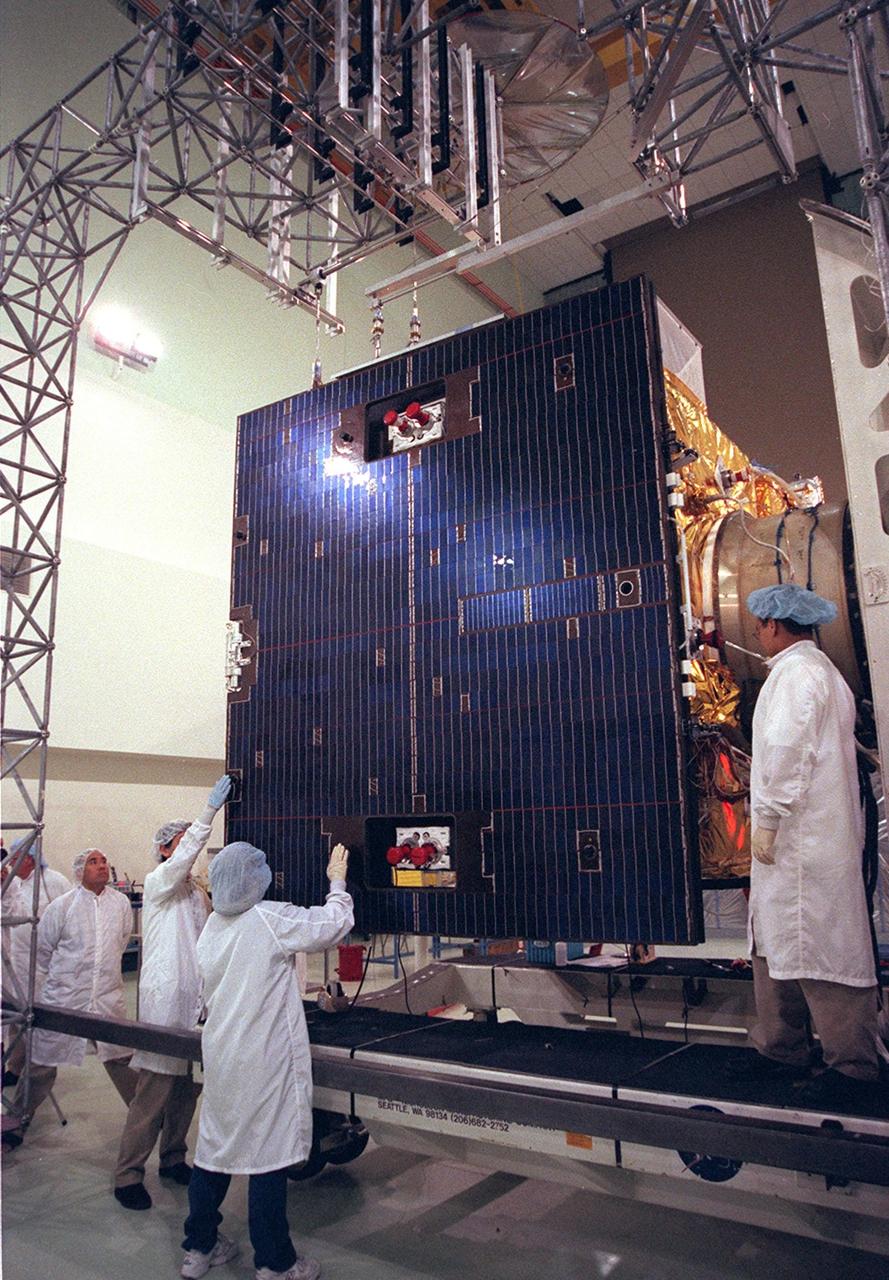 Workers at Astrotech, Titusville, Fla., prepare to open the solar panel on the GOES-M satellite. The GOES-M provides weather imagery and quantitative sounding data used to support weather forecasting, severe storm tracking and meteorological research. The satellite is scheduled to launch July 12 on an Atlas-IIA booster, Centaur upper stage from Cape Canaveral Air Force Station