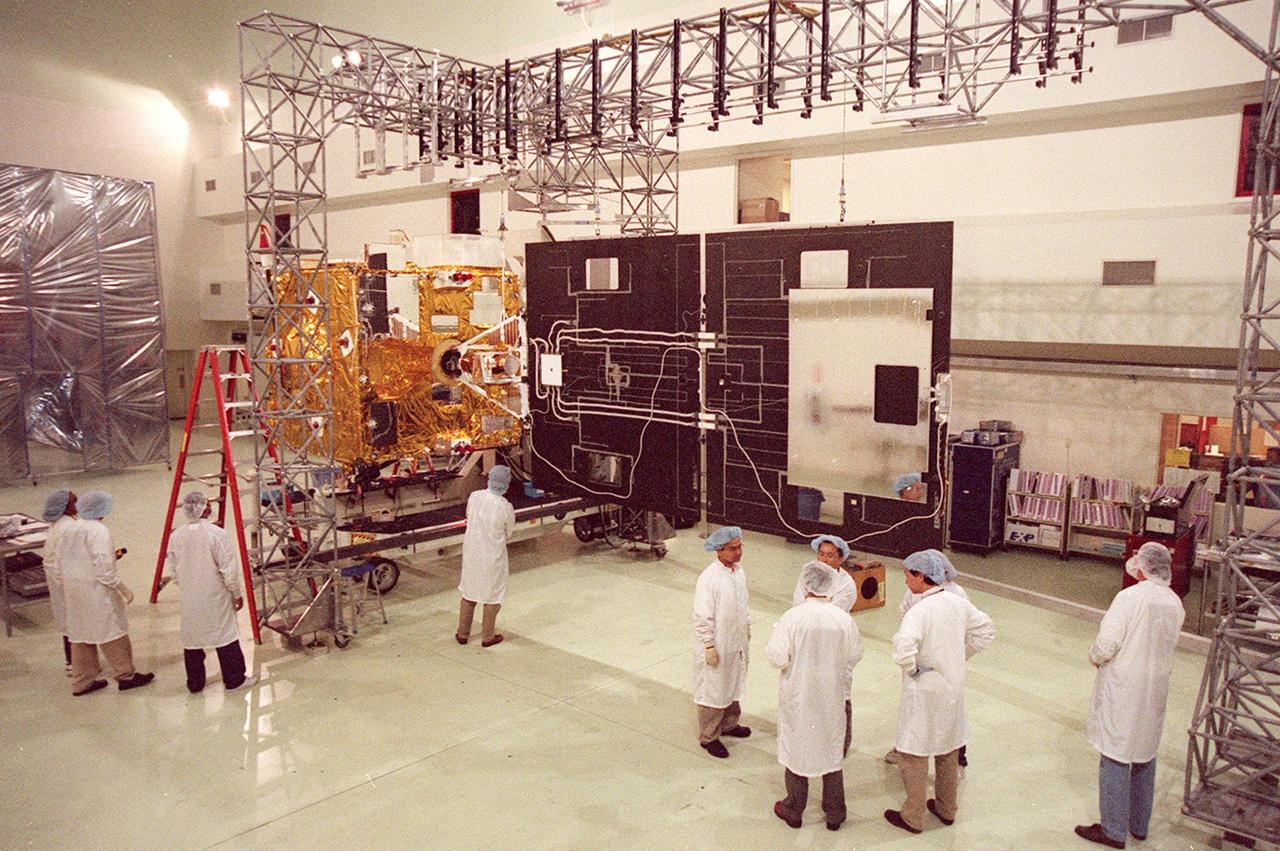 Workers (at left) at Astrotech, Titusville, Fla., observe the inside of the solar panel on the GOES-M satellite. The GOES-M provides weather imagery and quantitative sounding data used to support weather forecasting, severe storm tracking and meteorological research. The satellite is scheduled to launch July 12 on an Atlas-IIA booster, Centaur upper stage from Cape Canaveral Air Force Station