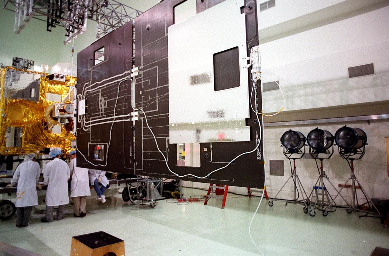 Workers at Astrotech, Titusville, Fla., confer about their findings after opening the solar panel on the GOES-M satellite. The GOES-M provides weather imagery and quantitative sounding data used to support weather forecasting, severe storm tracking and meteorological research. The satellite is scheduled to launch July 12 on an Atlas-IIA booster, Centaur upper stage from Cape Canaveral Air Force Station