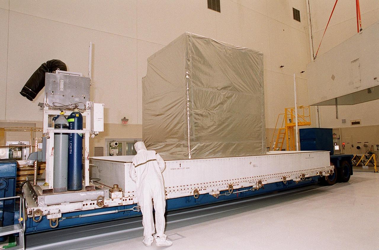 KENNEDY SPACE CENTER, FLA. -- Inside the Spacecraft Assembly and Encapsulation Facility 2, a covered Microwave Anisotropy Probe (MAP) satellite is revealed after removal of the container (far right). MAP will undergo testing in the SAEF-2 before its scheduled launch June 30 from Cape Canaveral Air Force Station on a Delta II rocket into a lunar-assisted trajectory to the Sun-Earth for a 27-month mission (3 months transit, 24 months observing). The MAP instrument consists of a set of passively cooled microwave radiometers with 1.4x 1.6-meter diameter primary reflectors to provide the desired angular resolution. MAP measures small fluctuations in the temperature of the cosmic microwave background radiation to an accuracy of one millionth of a degree. These measurements should reveal the size, matter content, age, geometry and fate of the universe. They will also reveal the primordial structure that grew to form galaxies and will test ideas about the origins of these primordial structures. The MAP instrument will be continuously shaded from the Sun, Earth, and Moon by the spacecraft. It is a product of Goddard Space Flight Center in partnership with Princeton University