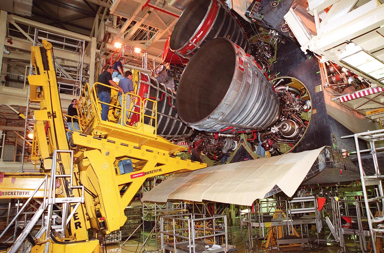 KENNEDY SPACE CENTER, FLA. -- The new block 2 engine for the orbiter Atlantis is moved into place next to the other two engines. The work is being done in the Orbiter Processing Facility bay 3. The engine will have its first flight on mission STS-104, scheduled for launch June 14. The Block II Main Engine configuration is manufactured by Boeing Rocketdyne in Canoga Park, Calif., and includes a new Pratt & Whitney high-pressure fuel turbo pump. Engine improvements are managed by NASA’s Marshall Space Flight Center in Huntsville, Ala. Each Space Shuttle Main Engine is 14 feet (4.3 meters) long, weighs about 7,000 pounds (3,175 kilograms), and is 7.5 feet (2.3 meters) in diameter at the end of the nozzle