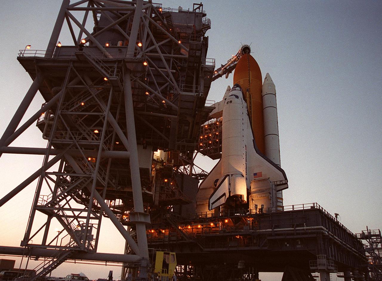KENNEDY SPACE CENTER, Fla. -- In the glow of a setting sun, Space Shuttle Endeavour is revealed after the rollback of the Rotating Service Structure (left) on Launch Pad 39A. At the top of the external tank can be seen the “beanie cap,” a venting apparatus at the end of the Gaseous Oxygen Vent Arm. Endeavour is expected to lift off on mission STS-100 on April 19, carrying the Multi-Purpose Logistics Module Raffaello and the Canadian robotic arm, SSRMS, with a crew of seven to the International Space Station