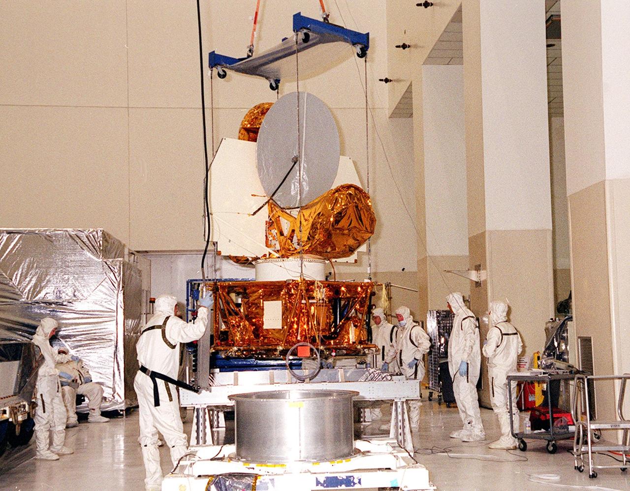 KENNEDY SPACE CENTER, FLA. --  Workers in the Spacecraft Assembly and Encapsulation Facility 2 stand by while the Microwave Anisotropy Probe (MAP) is lifted to place it on a workstand. Several milestones must be completed while MAP is at SAEF-2, including antenna installations, solar array installation, solar array deployment and illumination testing, a spacecraft comprehensive performance test, fueling with hydrazine propellant and a spin balance test. MAP will then be ready for integration with the solid propellant Payload Assist Module upper stage booster. MAP is scheduled for launch June 30 from Cape Canaveral Air Force Station on a Delta II rocket into a lunar-assisted trajectory to the Sun-Earth for a 27-month mission. The MAP instrument consists of a set of passively cooled microwave radiometers with 1.4x 1.6-meter diameter primary reflectors to provide the desired angular resolution. MAP measures small fluctuations in the temperature of the cosmic microwave background radiation to an accuracy of one millionth of a degree These measurements should reveal the size, matter content, age, geometry and fate of the universe. They will also reveal the primordial structure that grew to form galaxies and will test ideas about the origins of these primordial structures. The MAP instrument will be continuously shaded from the Sun, Earth, and Moon by the spacecraft. It is a product of Goddard Space Flight Center in partnership with Princeton University