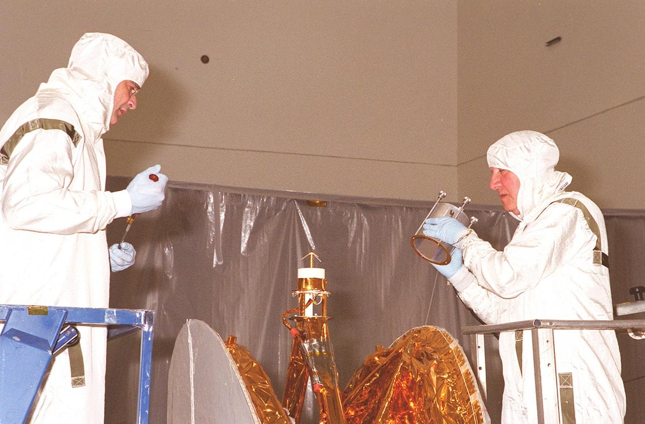 KENNEDY SPACE CENTER, FLA. --  Workers in the Spacecraft Assembly and Encapsulation Facility 2 place an antenna on the Microwave Anisotropy Probe (MAP). Several other milestones must be completed while MAP is at SAEF-2, including solar array installation, solar array deployment and illumination testing, a spacecraft comprehensive performance test, fueling with hydrazine propellant and a spin balance test. MAP will then be ready for integration with the solid propellant Payload Assist Module upper stage booster. MAP is scheduled for launch June 30 from Cape Canaveral Air Force Station on a Delta II rocket into a lunar-assisted trajectory to the Sun-Earth for a 27-month mission. The MAP instrument consists of a set of passively cooled microwave radiometers with 1.4x 1.6-meter diameter primary reflectors to provide the desired angular resolution. MAP measures small fluctuations in the temperature of the cosmic microwave background radiation to an accuracy of one millionth of a degree These measurements should reveal the size, matter content, age, geometry and fate of the universe. They will also reveal the primordial structure that grew to form galaxies and will test ideas about the origins of these primordial structures. The MAP instrument will be continuously shaded from the Sun, Earth, and Moon by the spacecraft. It is a product of Goddard Space Flight Center in partnership with Princeton University