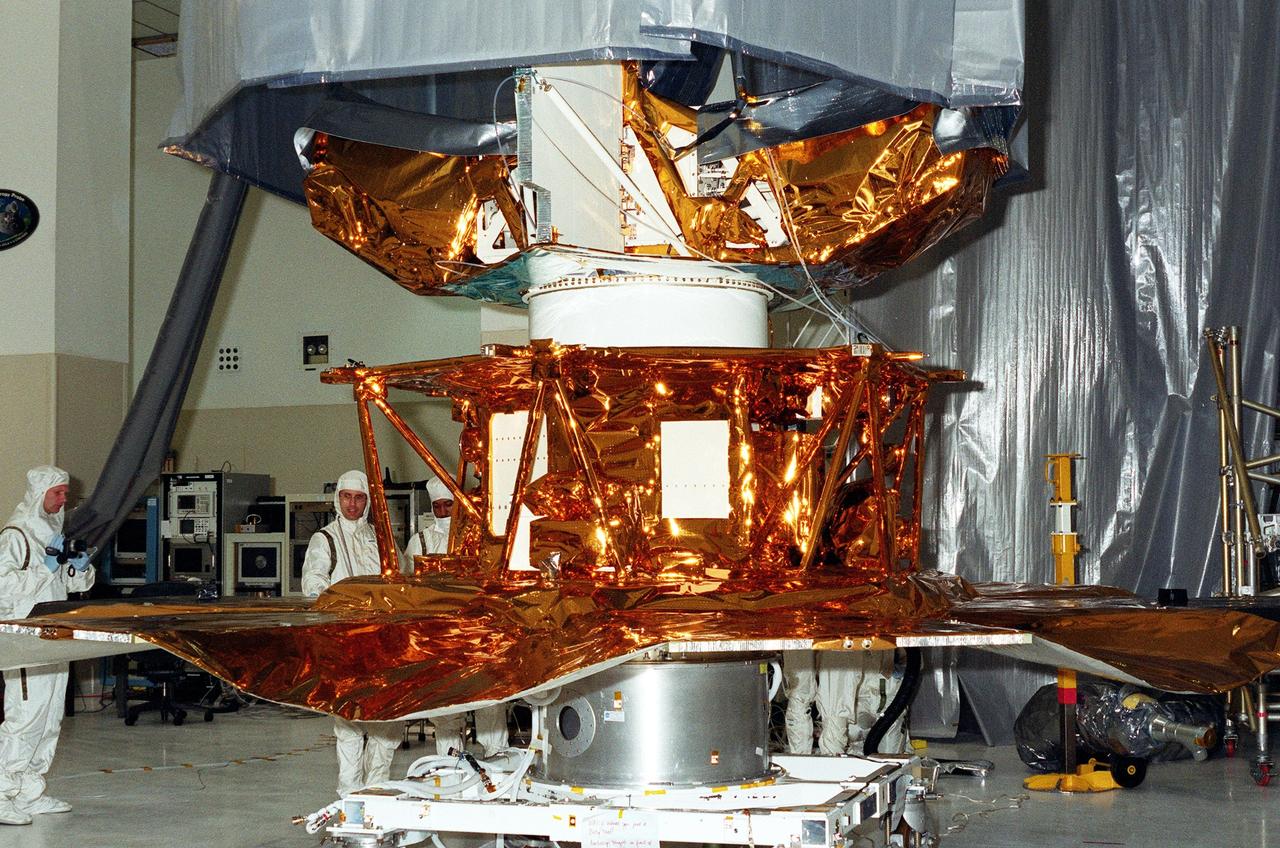 KENNEDY SPACE CENTER, FLA. -- Scientists and other workers watch as the solar panels on the Microwave Anisotropy Probe (MAP) spacecraft are deployed in the Spacecraft Assembly and Encapsulation Facility 2. MAP is scheduled for launch on June 30 aboard a Boeing Delta II rocket. The launch will place MAP into a lunar-assisted trajectory to the Sun-Earth for a 27-month mission. The probe will measure small fluctuations in the temperature of the cosmic microwave background radiation to an accuracy of one millionth of a degree. These measurements should reveal the size, matter content, age, geometry and fate of the universe. They will also reveal the primordial structure that grew to form galaxies and will test ideas about the origins of these primordial structures. The MAP instrument will be continuously shaded from the Sun, Earth, and Moon by the spacecraft. The probe is a product of Goddard Space Flight Center in partnership with Princeton University