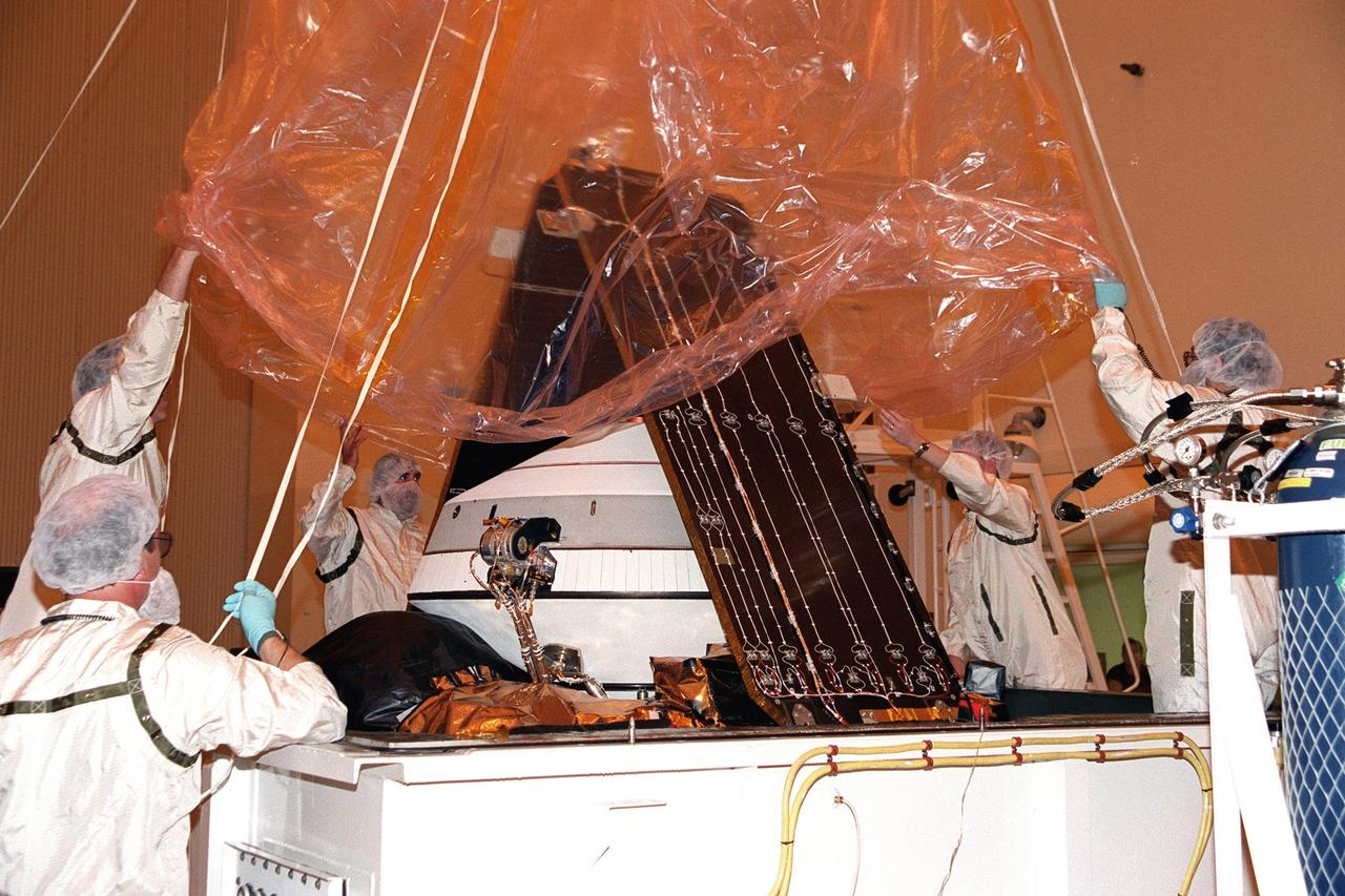 KENNEDY SPACE CENTER, Fla. -- In the Payload Hazardous Servicing Facility, workers lift the protective wrapping from Genesis - a spacecraft designed to collect samples of solar wind particles and return them to Earth so that scientists can study the exact composition of the Sun and probe the solar system’s origin. Genesis will be moved to a workstand for processing, which includes a functional test, electrical systems test and deployment of the solar arrays. Genesis is scheduled to be launched on a Delta II Lite launch vehicle from Complex 17-A, Cape Canaveral Air Force Station, July 30, at 12:36 p.m. EDT