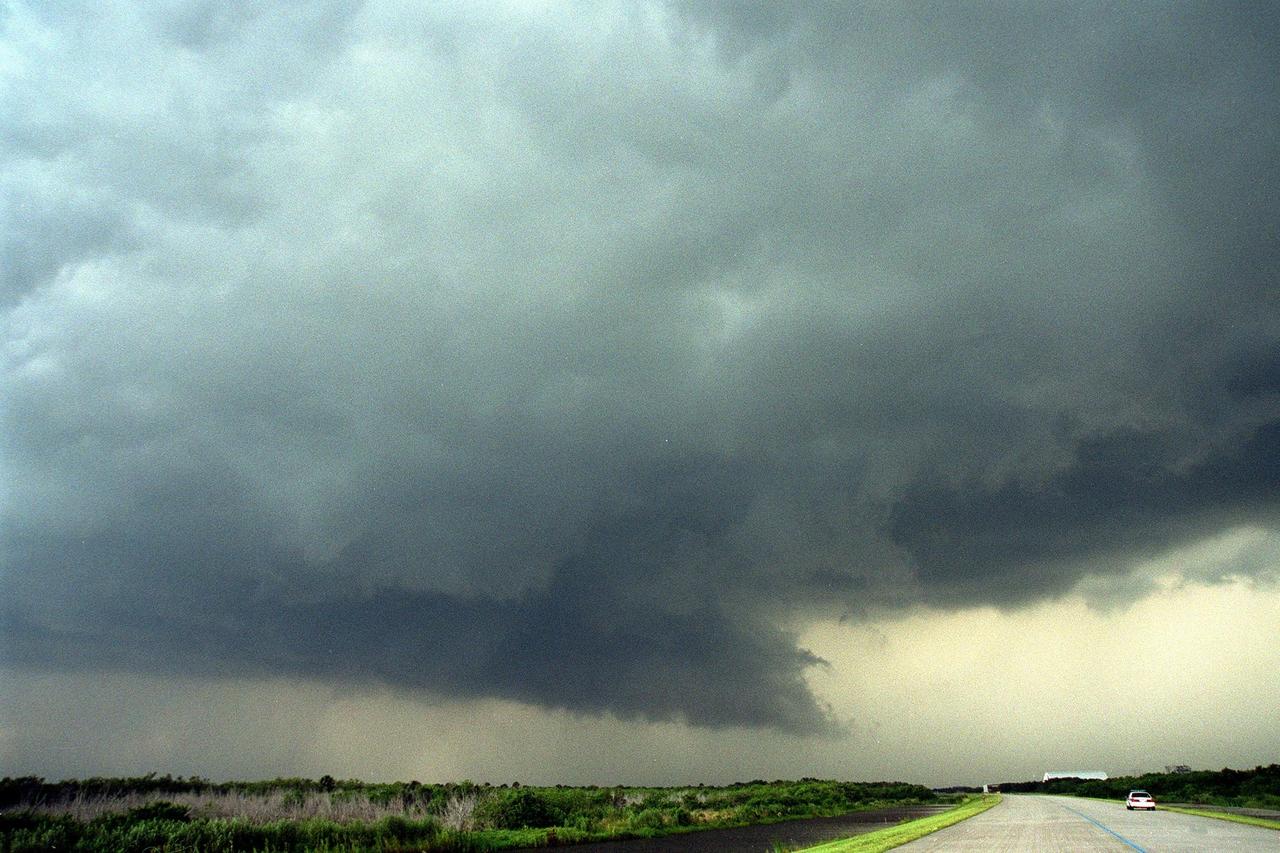 KENNEDY SPACE CENTER, Fla. -- Dark clouds and strong winds seem almost to touch the ground near the tow-way leading from the Shuttle Landing Facility (SLF). In the background (right) can be seen the new hangar at the SLF and the mate/demate device. The cloud formation is proceeding across the SLF towards the Vehicle Assembly Building