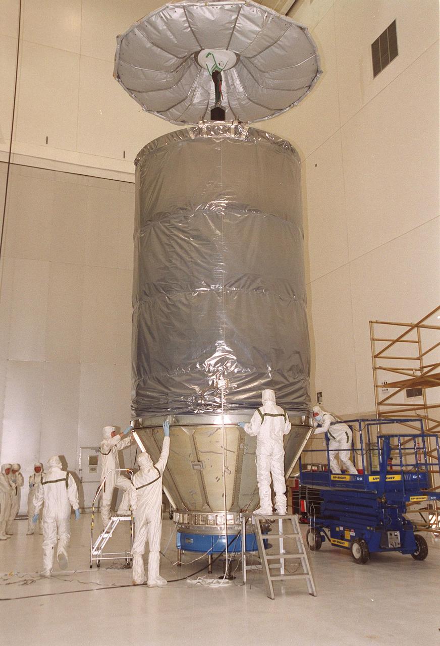 KENNEDY SPACE CENTER, Fla. -- In KSC’s Spacecraft Assembly and Encapsulation Facility -2, workers adjust the canister as it is lowered over the Microwave Anisotropy Probe (MAP). The spacecraft will be transported to Launch Complex 17, Cape Canaveral Air Force Station. Launch of MAP via a Boeing Delta II rocket is scheduled for June 30