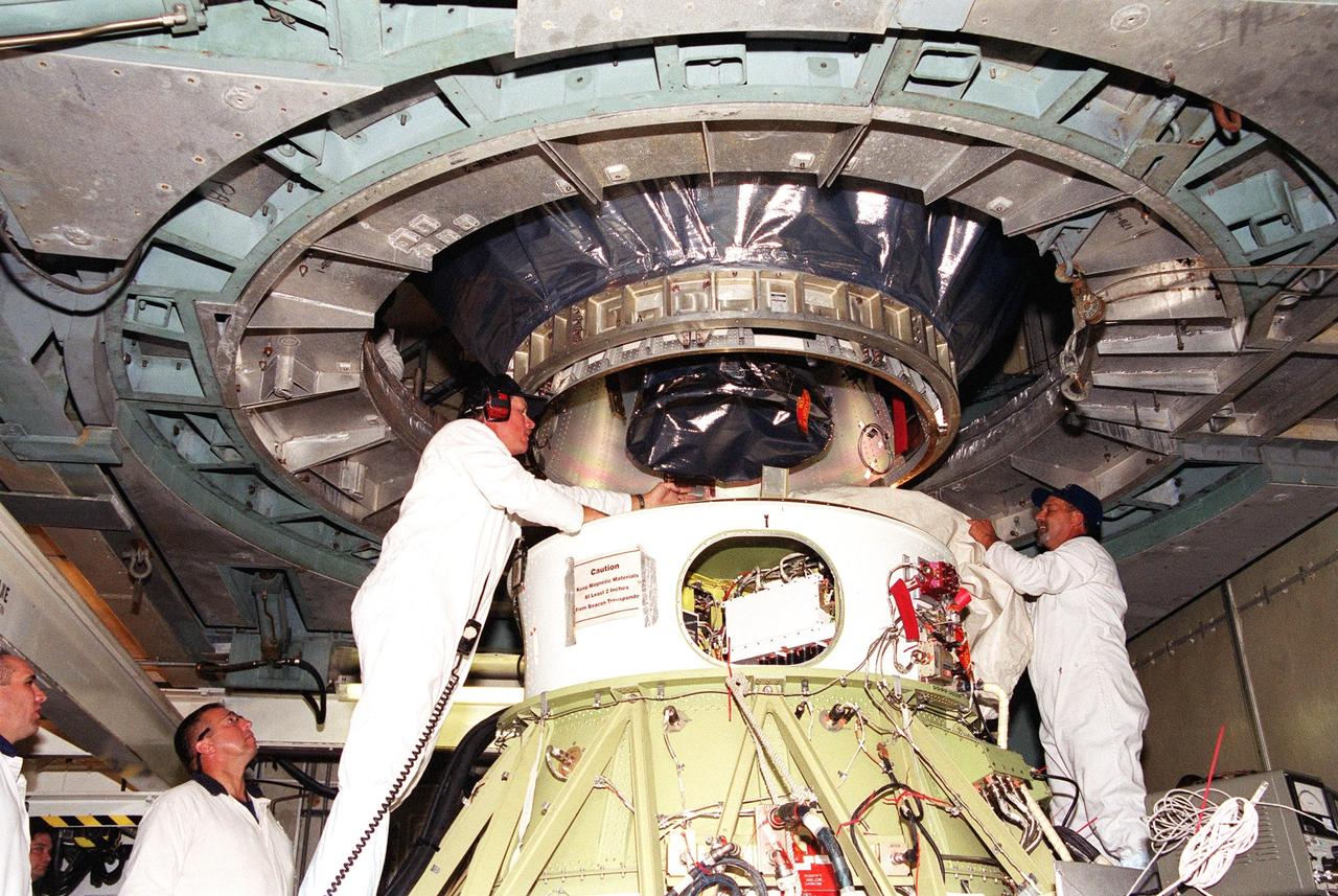 KENNEDY SPACE CENTER, Fla. -- At Launch Complex 17-B, Cape Canaveral Air Force Station, workers keep watch while the Microwave Anisotropy Probe (MAP) is lowered into position on the Delta II rocket below. Launch of MAP via a Boeing Delta II rocket is scheduled for June 30. The launch will place MAP into a lunar-assisted trajectory to the Sun-Earth for a 27-month mission. The probe will measure small fluctuations in the temperature of the cosmic microwave background radiation to an accuracy of one millionth of a degree. These measurements should reveal the size, matter content, age, geometry and fate of the universe. They will also reveal the primordial structure that grew to form galaxies and will test ideas about the origins of these primordial structures
