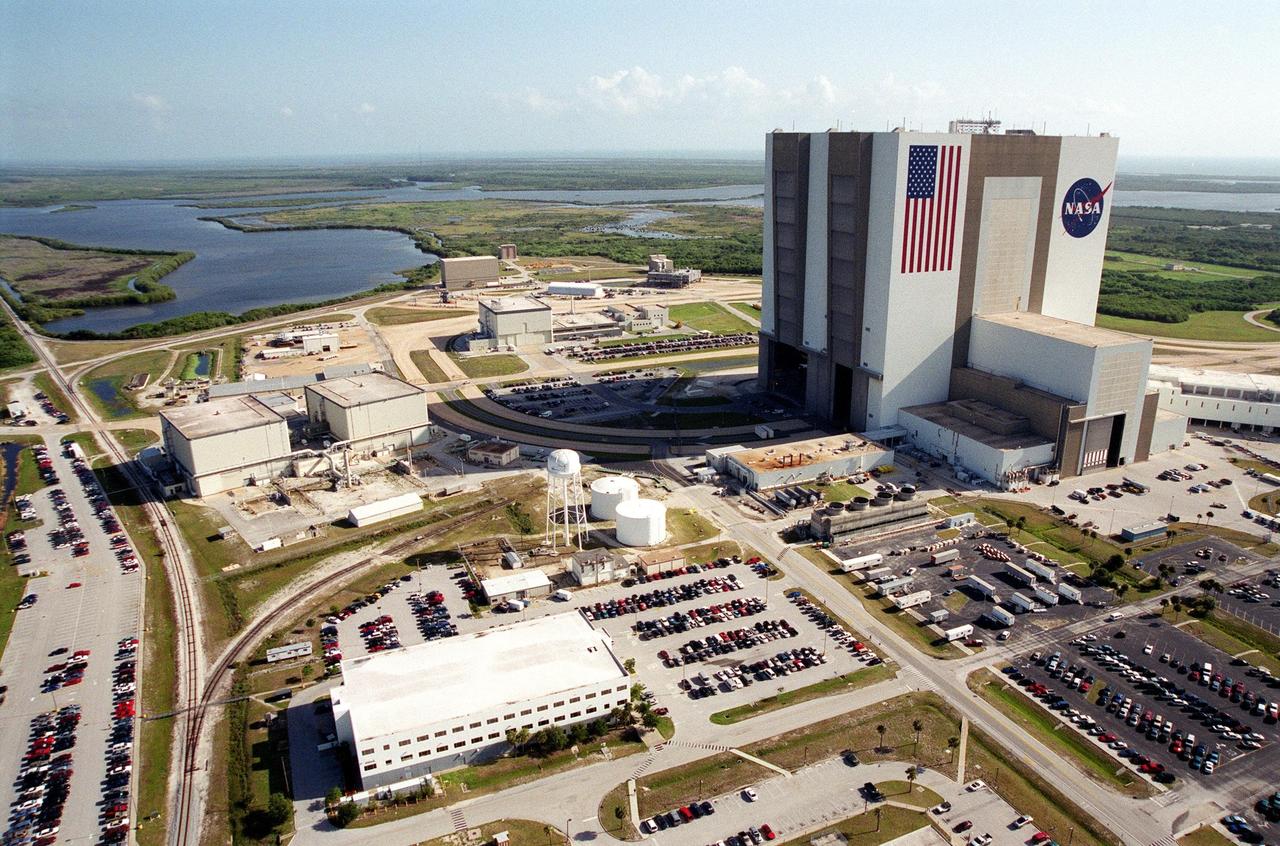 KENNEDY SPACE CENTER, Fla. -- An aerial view of Launch Complex 39 shows the south and west sides of the Vehicle Assembly Building. The curved roadway heading to the VAB leads to the high bay 2, the Safe Haven facility constructed in 2000. The white building in the foreground is the Processing Control Center. Beyond it is the Orbiter Processing Facility, bays 1 and 2. The OPF bay 3 is farther still, closer to the VAB. Farther in the background are the waters of Banana Creek in the Merritt Island National Wildlife Refuge