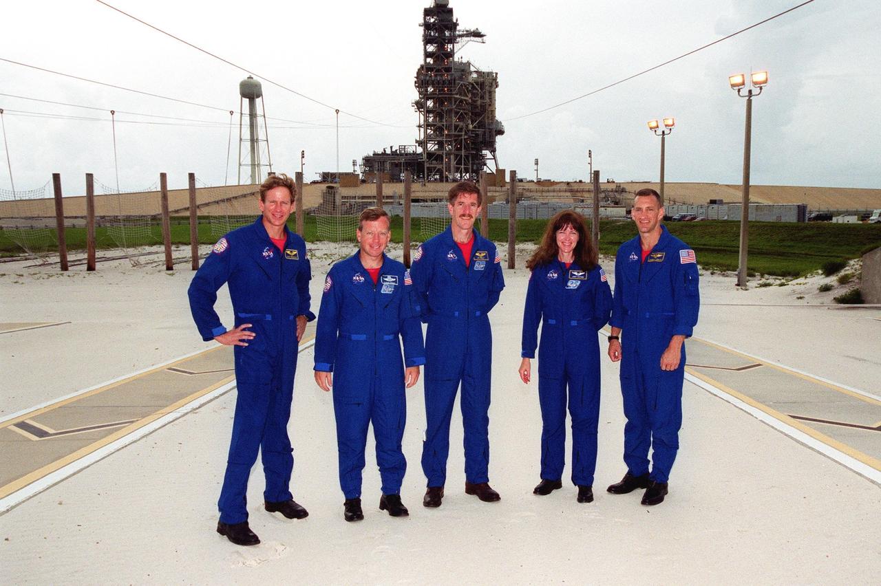 KENNEDY SPACE CENTER, Fla. -- The STS-104 crew poses for a photo in the slidewire basket grounds near Launch Pad 39B and Space Shuttle Atlantis (behind them). Standing left to right are Mission Specialist Michael L. Gernhardt, Commander Steven W. Lindsey, Mission Specialists James F. Reilly and Janet Lynn Kavandi, and Pilot Charles O. Hobaugh. The crew is taking part in Terminal Countdown Demonstration Test activities, which include emergency exit training, opportunities to inspect their mission payloads in the orbiter’s payload bay and simulated countdown exercises. The launch of Atlantis on mission STS-104 is scheduled July 12 from Launch Pad 39B. The mission is the 10th flight to the International Space Station and carries the Joint Airlock Module