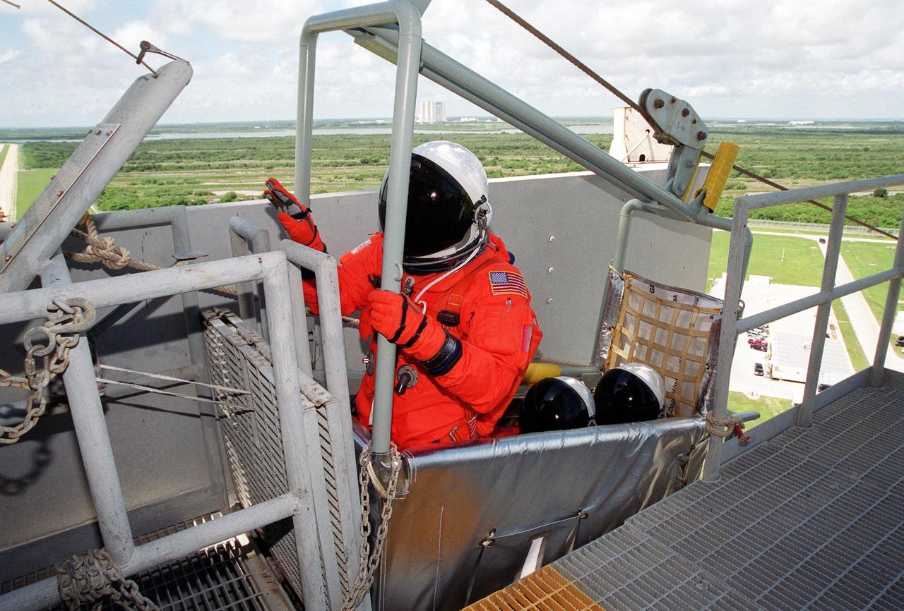 KENNEDY SPACE CENTER, Fla. -- On Launch Pad 39B, STS-104 Mission Specialist James F. Reilly reaches for the lever that will send the slidewire basket he is in speeding to the landing field below. Seated behind Reilly are Mission Specialists Janet Lynn Kavandi and Michael L. Gernhardt. They and other crew members are taking part in Terminal Countdown Demonstration Test activities, which include the emergency egress training and a simulated countdown exercise. The launch of Atlantis on mission STS-104 is scheduled July 12. The mission is the 10th flight to the International Space Station and carries the Joint Airlock Module and High Pressure Gas Assembly