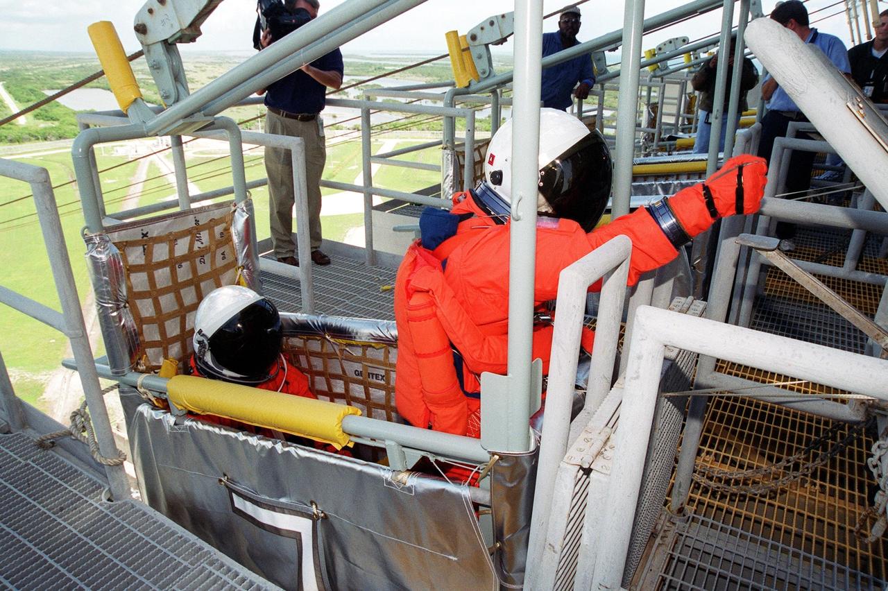 KENNEDY SPACE CENTER, Fla. -- On Launch Pad 39B, STS-104 Commander Steven W. Lindsey (right) reaches for the lever that will send the slidewire basket he is in speeding to the landing field below. Seated behind Lindsey is Pilot Charles O. Hobaugh. They and other crew members are taking part in Terminal Countdown Demonstration Test activities, which include this emergency egress training and a simulated countdown exercise. The launch of Atlantis on mission STS-104 is scheduled July 12. The mission is the 10th flight to the International Space Station and carries the Joint Airlock Module and High Pressure Gas Assembly