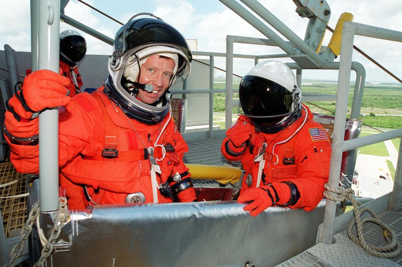 KENNEDY SPACE CENTER, Fla. -- On Launch Pad 39B, STS-104 Commander Steven W. Lindsey (left) smiles after completing emergency egress training in the slidewire basket he is in. At right is Pilot Charles O. Hobaugh. They and other crew members are taking part in Terminal Countdown Demonstration Test activities, which include the emergency egress training and a simulated countdown exercise. The launch of Atlantis on mission STS-104 is scheduled July 12. The mission is the 10th flight to the International Space Station and carries the Joint Airlock Module and High Pressure Gas Assembly