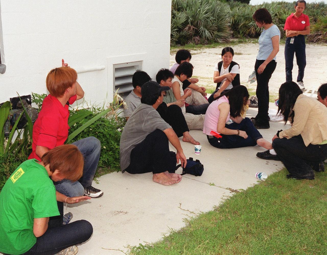 KENNEDY SPACE CENTER, Fla. -- Chinese foreign nationals (on right), who arrived unannounced on Kennedy Space Center grounds, wait for representatives of Immigration and Naturalization Services to transport them to an office in Orlando for processing