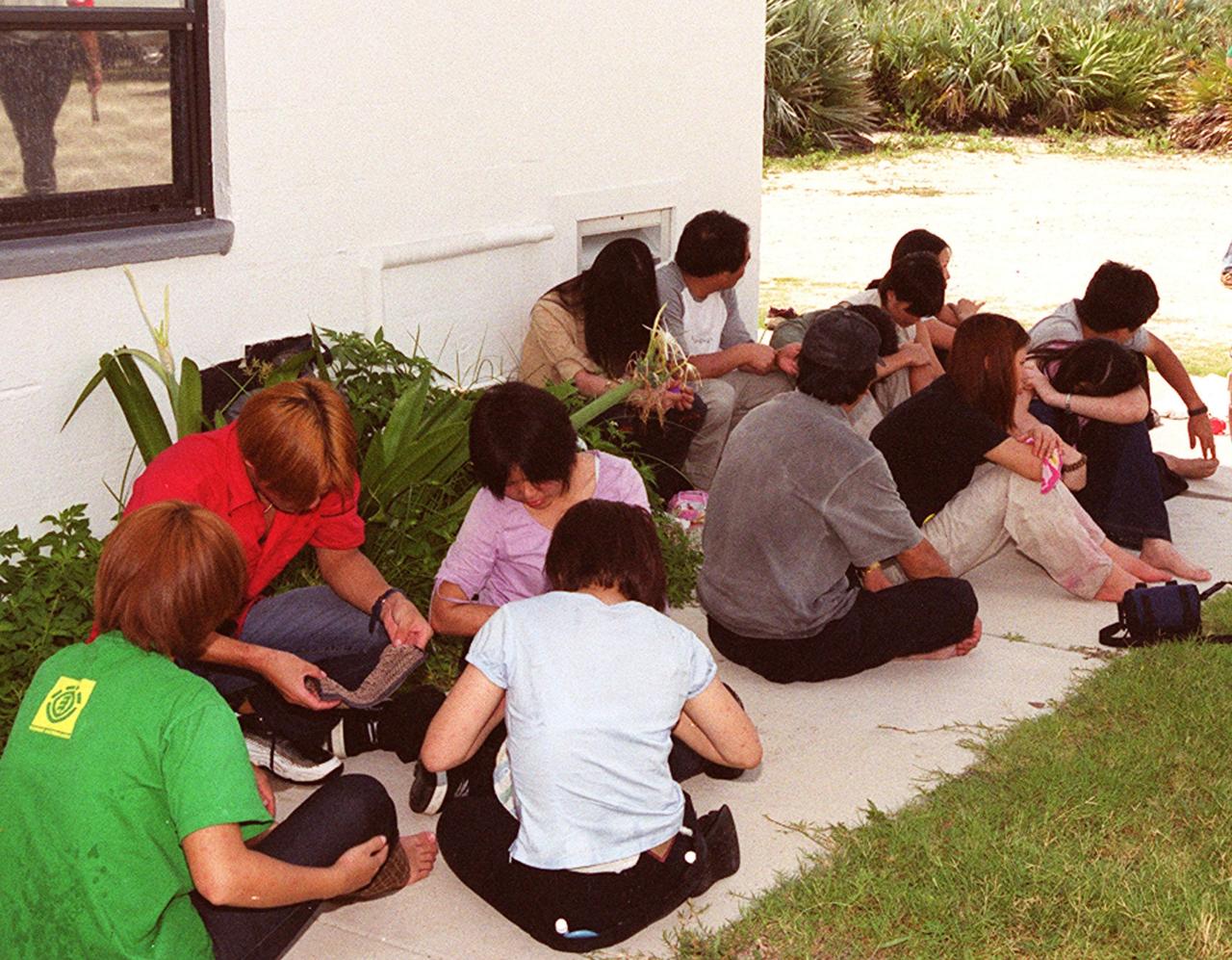 KENNEDY SPACE CENTER, Fla. -- Chinese foreign nationals (center and right), who arrived unannounced on Kennedy Space Center grounds, wait for representatives of Immigration and Naturalization Services to transport them to an office in Orlando for processing