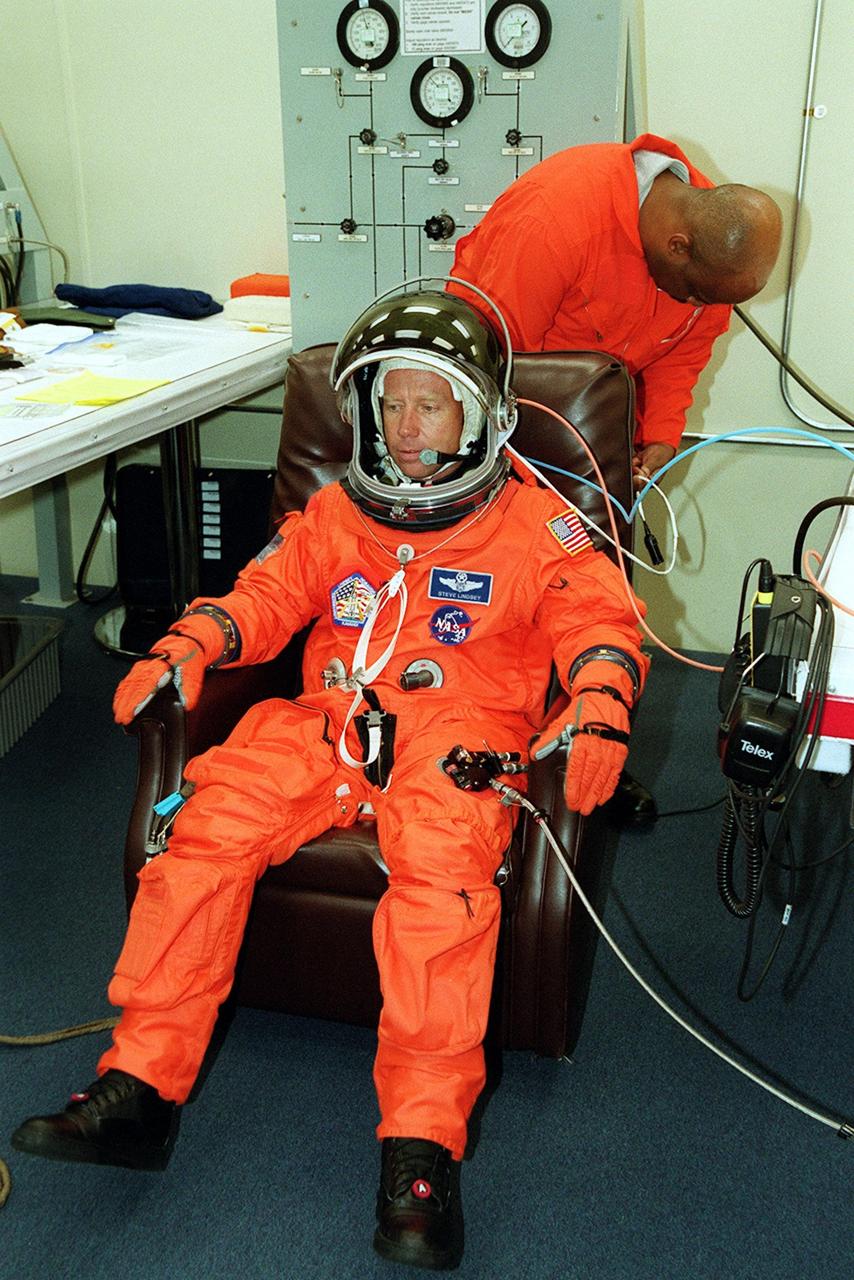 KENNEDY SPACE CENTER, Fla. -- STS-104 Commander Steven W. Lindsey is helped with suit check. He and other crew members are making final preparations for launch July 12 from Launch Pad 39B. Mission STS-104 is the 10th assembly flight to the International Space Station and carries the Joint Airlock Module, which will become the primary path for spacewalk entry and departure using both U.S. spacesuits and the Russian Orlan spacesuit for EVA activity