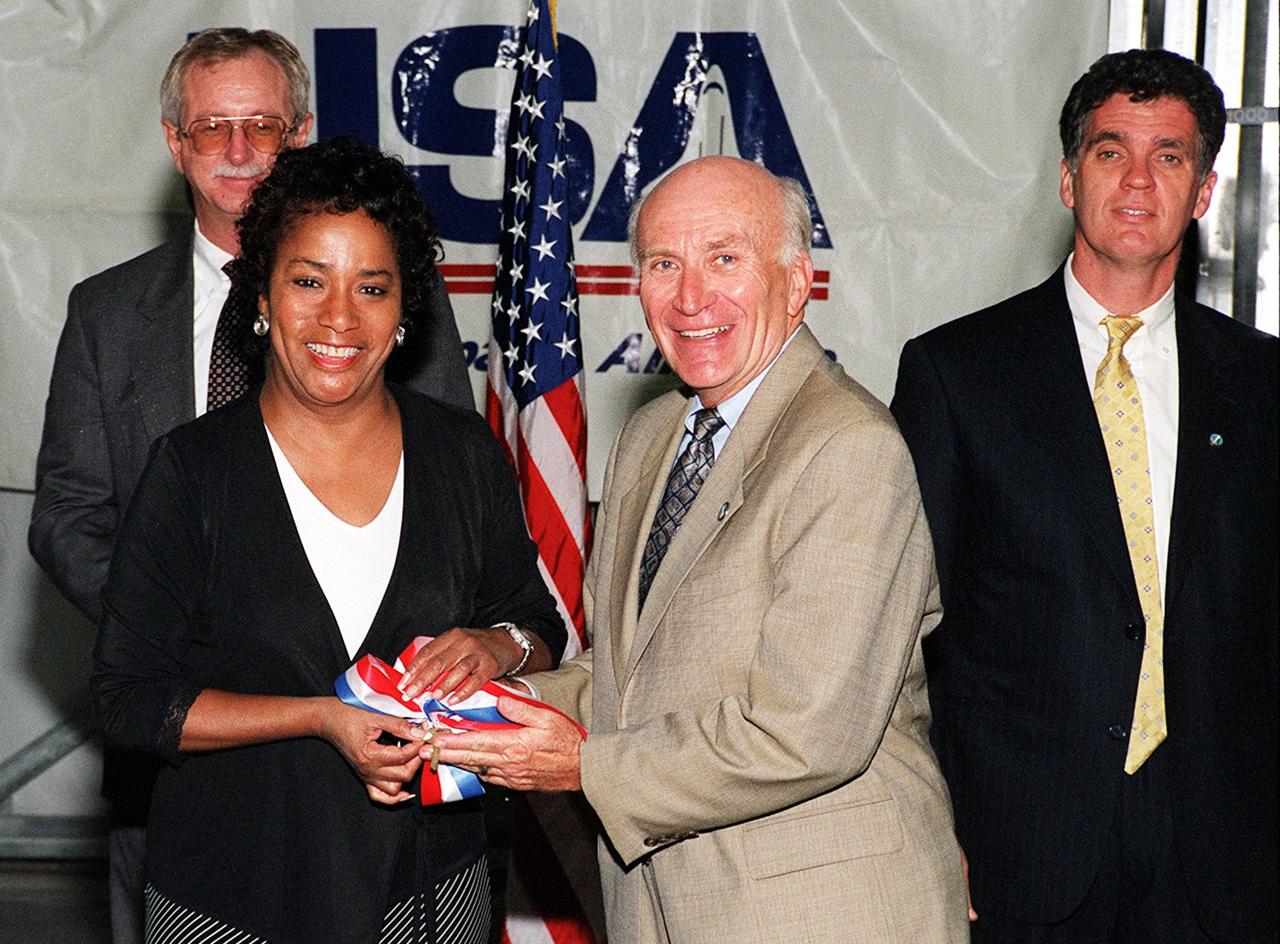KENNEDY SPACE CENTER, Fla. -- After the signing of a lease agreement between Spaceport Florida Authority (SFA) and United Space Alliance (USA) for the use of a hangar at Kennedy Space Center, (foreground left) Marcie Harris, USA site director, and (foreground right) Ed Gormel, Spaceport Florida executive director, hold a symbolic ribbon. Behind them are (left) Greg Popp, Spaceport Florida business manager, and (right) Congressman Dave Weldon. The hangar was originally developed by the state as part of a joint NASA/SFA Reusable Launch Vehicle Support Complex at KSC. USA plans to use the state-developed 50,000-square-foot facility to store and maintain Space Shuttle ground equipment