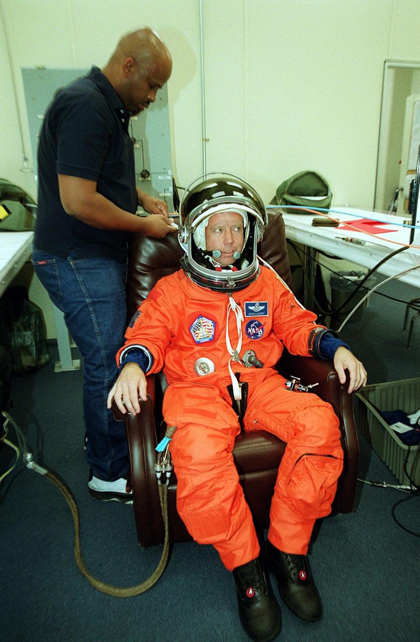 KENNEDY SPACE CENTER, Fla. -- STS-104 Commander Steven W. Lindsey gets help donning his launch and entry suit before heading to the launch pad. This launch will be his third space flight. Liftoff of Space Shuttle Atlantis on mission STS-104 is targeted for 5:04 a.m., July 12, from Launch Pad 39B. The primary payload on the mission is the joint airlock module, which will be added to the International Space Station. The airlock will be the primary path for Space Station spacewalk entry and departure for U.S. spacesuits, and will also support the Russian Orlan spacesuit for EVA activity