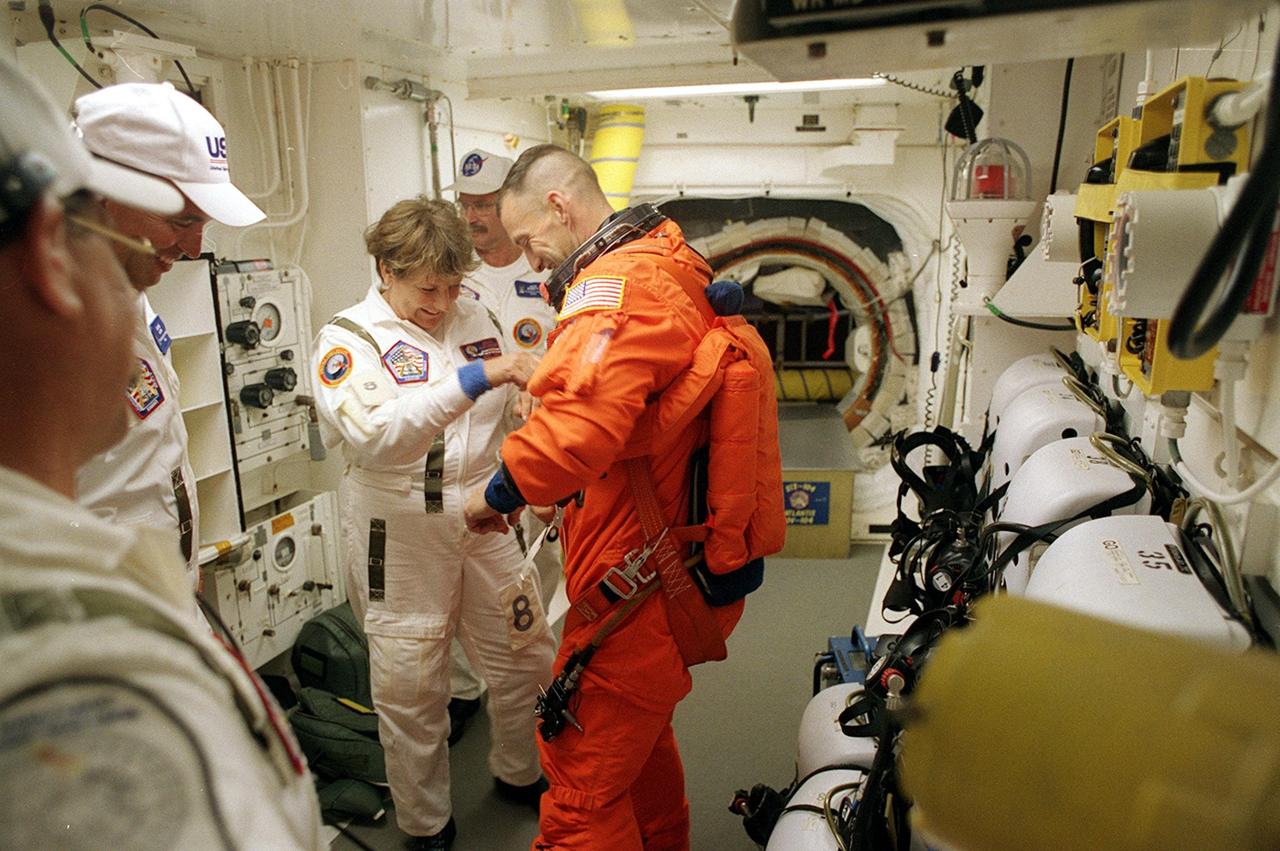 KENNEDY SPACE CENTER, Fla. -- In the White Room, STS-104 Pilot Charles O. Hobaugh (center) is helped by closeout crew members before entering Space Shuttle Atlantis. The White Room is an environmental chamber at the end of the Orbiter Access Arm that provides entry into the orbiter on the launch pad. Atlantis lifted off from Launch Pad 39B on time at 5:03:59 a.m. EDT. The 10th assembly flight to the International Space Station, the primary payload on the mission is the joint airlock module, which will require two spacewalks to attach it to the Space Station. The airlock will be the primary path for Space Station spacewalk entry and departure for U.S. spacesuits, and will also support the Russian Orlan spacesuit for EVA activity