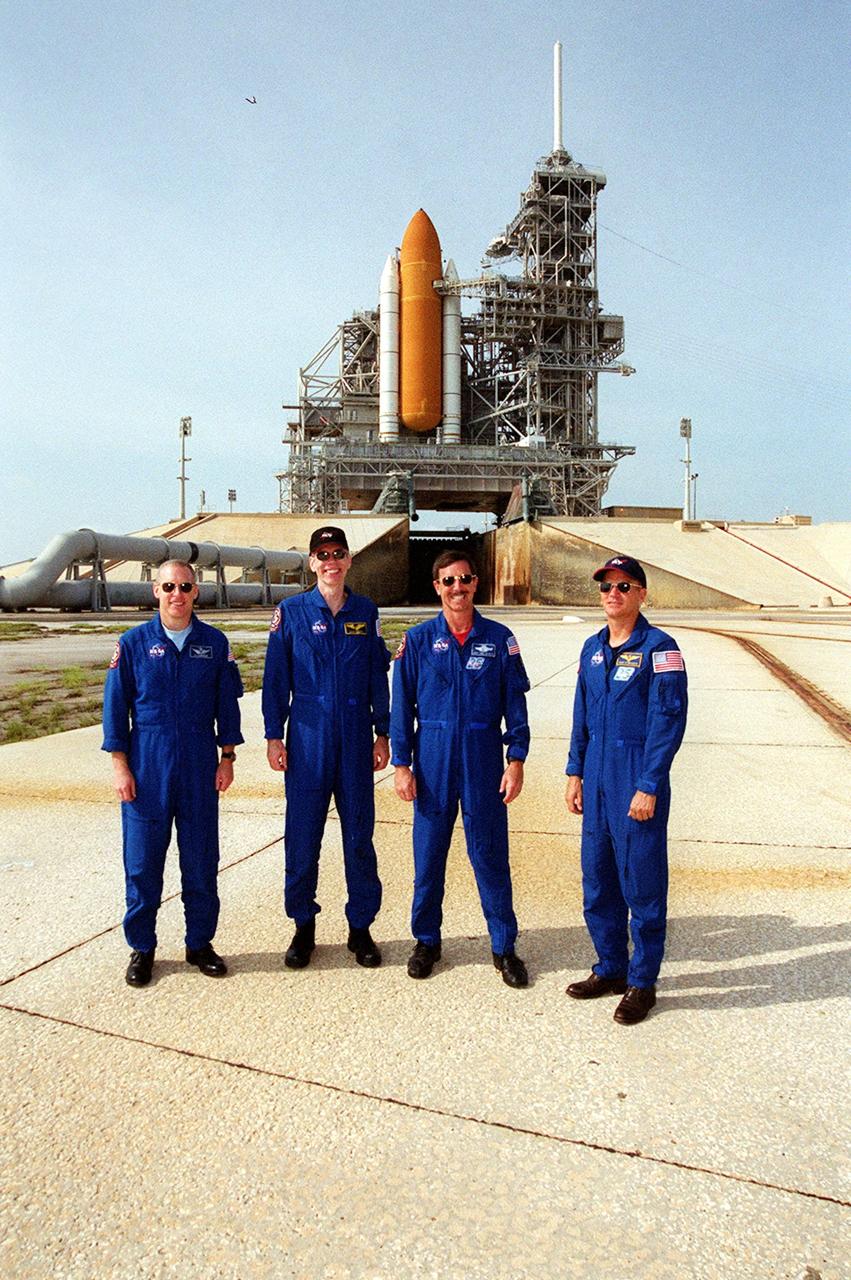 KENNEDY SPACE CENTER, Fla. -- The STS-105 crew poses at Launch Pad 39A after training exercises. Pictured (left to right), Mission Specialists Patrick Forrester and Daniel Barry, Commander Scott Horowitz and Pilot Rick Sturckow. They are taking part in Terminal Countdown Demonstration Test activities, along with the Expedition Three crew. The training includes emergency egress, a simulated launch countdown and familiarization with the payload. Mission STS-105 will be transporting the Expedition Three crew, several payloads and scientific experiments to the International Space Station aboard Space Shuttle Discovery, which is seen in the background. The current Expedition Two crew members on the Station will return to Earth on Discovery. Launch of Discovery is scheduled no earlier than Aug. 9, 2001