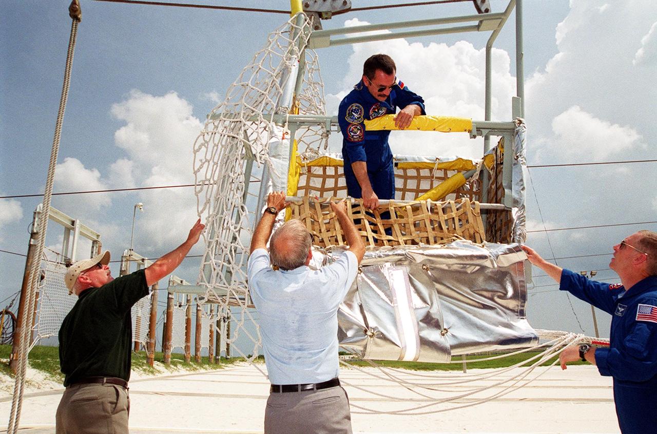 KENNEDY SPACE CENTER, Fla. -- Expedition Three crew member Mikhail Tyurin, a cosmonaut with the Russian Aviation and Space Agency, checks out the slidewire basket at Launch Pad 39A. At right is STS-105 Pilot Rick Sturckow. Both crews are at KSC to take part in Terminal Countdown Demonstration Test activities, which include emergency egress, a simulated launch countdown and familiarization with the payload. Mission STS-105 will be transporting the Expedition Three crew, several payloads and scientific experiments to the International Space Station aboard Discovery. The current Expedition Two crew members on the Station will return to Earth on Discovery. Launch of Discovery is scheduled no earlier than Aug. 9, 2001