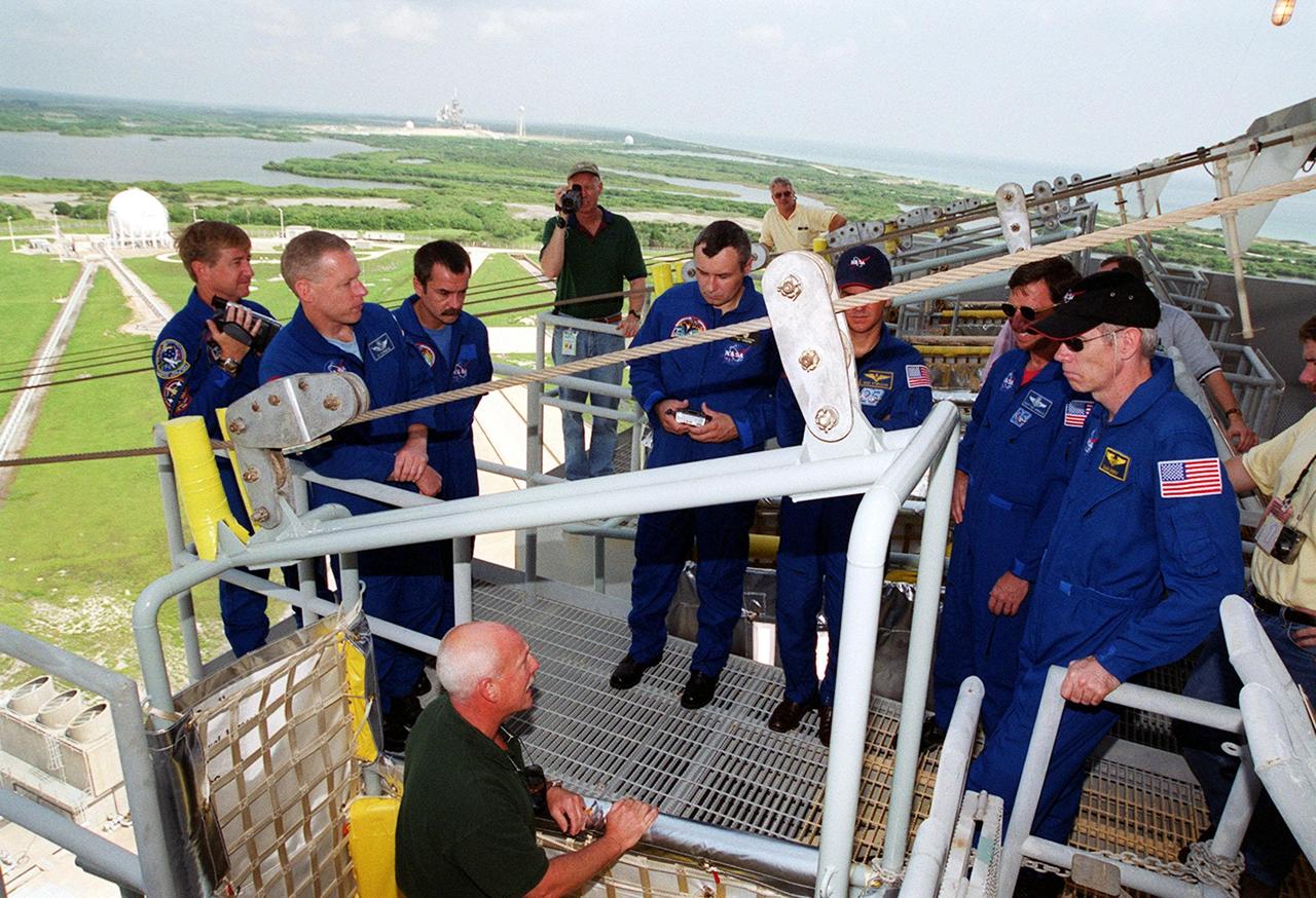 KENNEDY SPACE CENTER, Fla. -- On the 195-foot level of the Fixed Service Structure, Launch Pad 39A, the STS-105 and Expedition Three crews listen to instructions about use of the slidewire basket, part of emergency egress training at the pad. From left are Expedition Three Commander Frank Culbertson, STS-105 Pilot Rick Sturckow; cosmonauts Mikhail Tyurin and Vladimir Nikolaevich Dezhurov; Mission Specialist Patrick Forrester, Commander Scott Horowitz and Mission Specialist Daniel Barry. Both crews are at KSC to take part in Terminal Countdown Demonstration Test activities, which include the emergency egress training, a simulated launch countdown and familiarization with the payload. Mission STS-105 will be transporting the Expedition Three crew, several payloads and scientific experiments to the International Space Station aboard Discovery. The current Expedition Two crew members on the Station will return to Earth on Discovery. Launch of Discovery is scheduled no earlier than Aug. 9, 2001