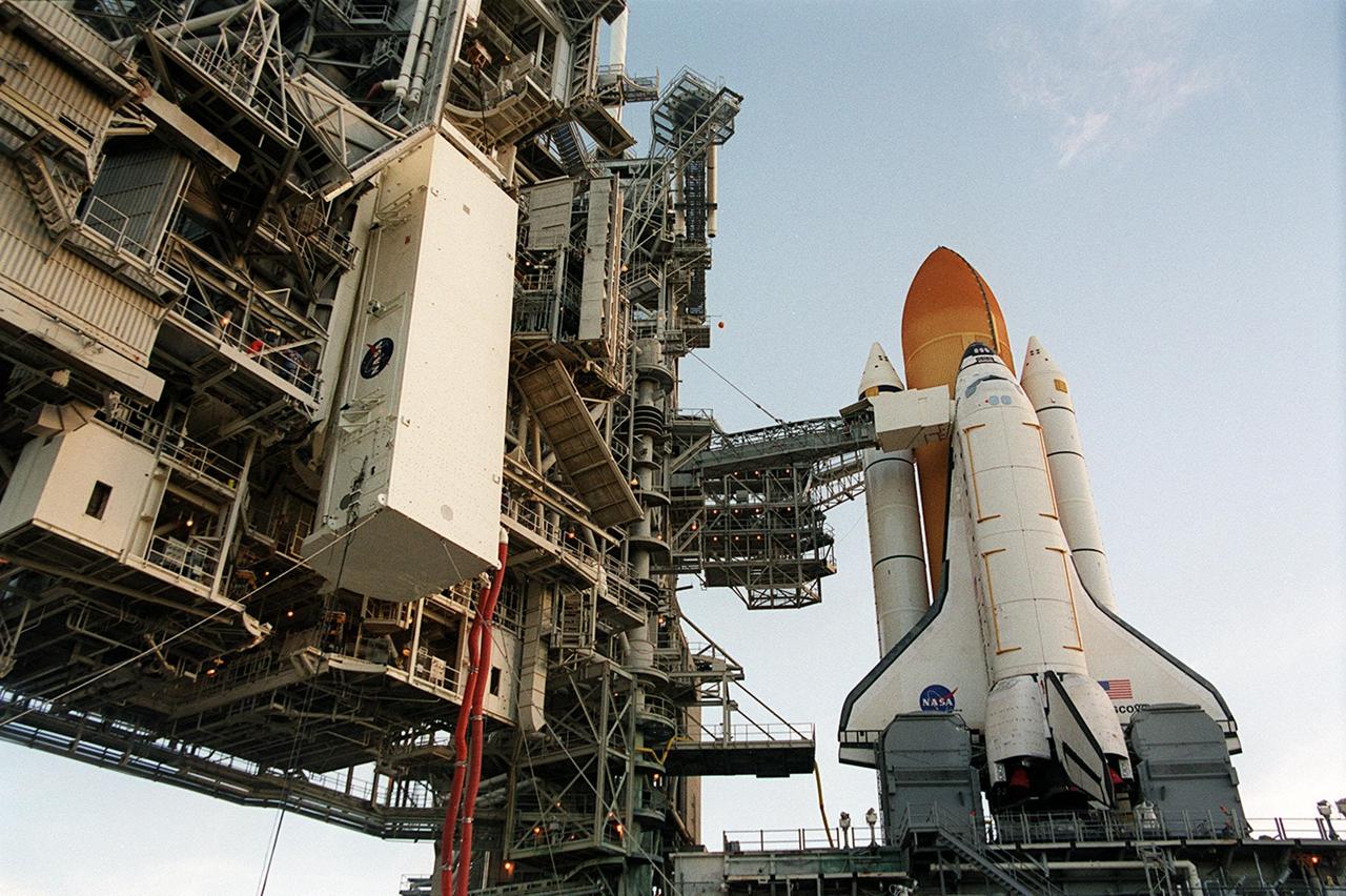 KENNEDY SPACE CENTER, Fla. -- The payload canister is lifted up the Rotating Service Structure on Launch Pad 39A. At right is Space Shuttle Discovery. Inside the canister are the primary payloads on mission STS-105, the Multi-Purpose Logistics Module Leonardo and the Integrated Cargo Carrier. The ICC holds several smaller payloads, the Early Ammonia Servicer and two experiment containers. The Early Ammonia Servicer consists of two nitrogen tanks that provide compressed gaseous nitrogen to pressurize the ammonia tank and replenish it in the thermal control subsystems of the Space Station. The ICC and MPLM will be lifted into the payload changeout room and then moved into the Discovery’s payload bay. The STS-105 mission includes a crew changeover on the International Space Station. Expedition Three will be traveling on Discovery to replace Expedition Two, who will return to Earth on board Discovery. Launch of STS-105 is scheduled for Aug. 9