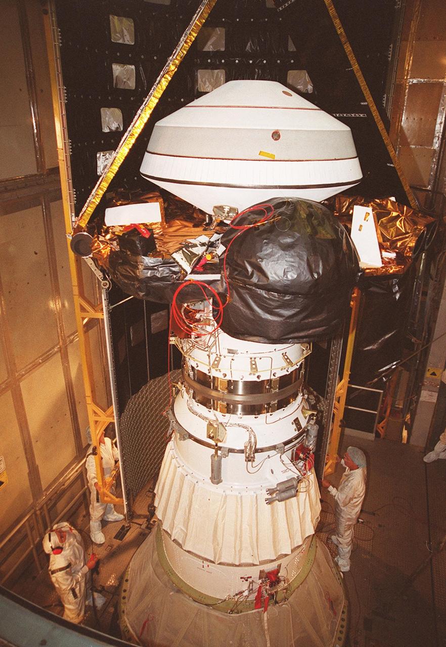 KENNEDY SPACE CENTER, Fla. -- Inside the mobile service tower at Launch Complex 17-A, Cape Canaveral Air Force Station, the Genesis spacecraft waits for the first half of the fairing to be installed (behind it). Genesis is 7.5 feet (2.3 meters) long and 6.6 feet (2 meters) wide, with a wingspan of solar array 26 feet (7.9 meters) tip to tip. Genesis will be on a robotic NASA space mission to collect and return to Earth just 10 to 20 micrograms -- or the weight of a few grains of salt -- of solar wind, invisible charged particles that flow outward from the Sun. This treasured smidgen of the Sun will be preserved in a special laboratory for study by scientists over the next century in search of answers to fundamental questions about the exact composition of our star and the birth of our solar system. The sample return capsule is 4.9 feet (1.5 meters) in diameter and 52 inches (1.31 meters) tall. The Genesis launch is scheduled for 12:36 p.m. EDT on July 30 from CCAFS