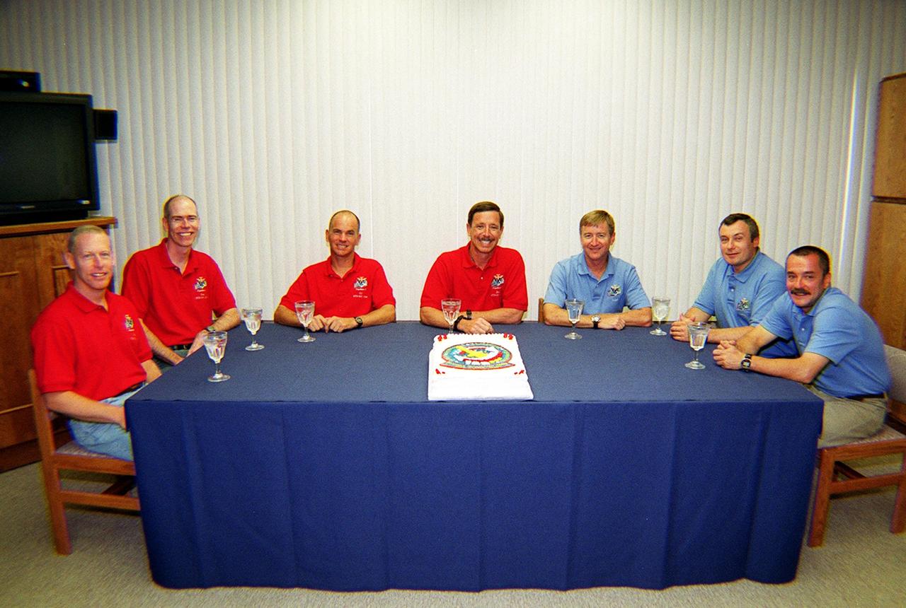 KENNEDY SPACE CENTER, Fla. -- Before suitup, the STS-105 and Expedition Three crews celebrate the pending launch with a special cake. In red shirts, seated left to right, are STS-105 Mission Specialists Patrick Forrester and Daniel Barry, Pilot Rick Sturckow and Commander Scott Horowitz. In blue shirts are the Expedition Three crew, Commander Frank Culbertson, Vladimir Dezhurov and Mikhail Tyurin. Dezhurov and Tyurin are cosmonauts with the Russian Aviation and Space Agency. On the mission, Discovery will be transporting the Expedition Three crew and several payloads and scientific experiments to the ISS, including the Early Ammonia Servicer (EAS) tank. The EAS, which will support the thermal control subsystems until a permanent system is activated, will be attached to the Station during two spacewalks. The three-member Expedition Two crew will be returning to Earth aboard Discovery after a five-month stay on the Station. Launch is scheduled for 5:38 p.m. EDT Aug. 9