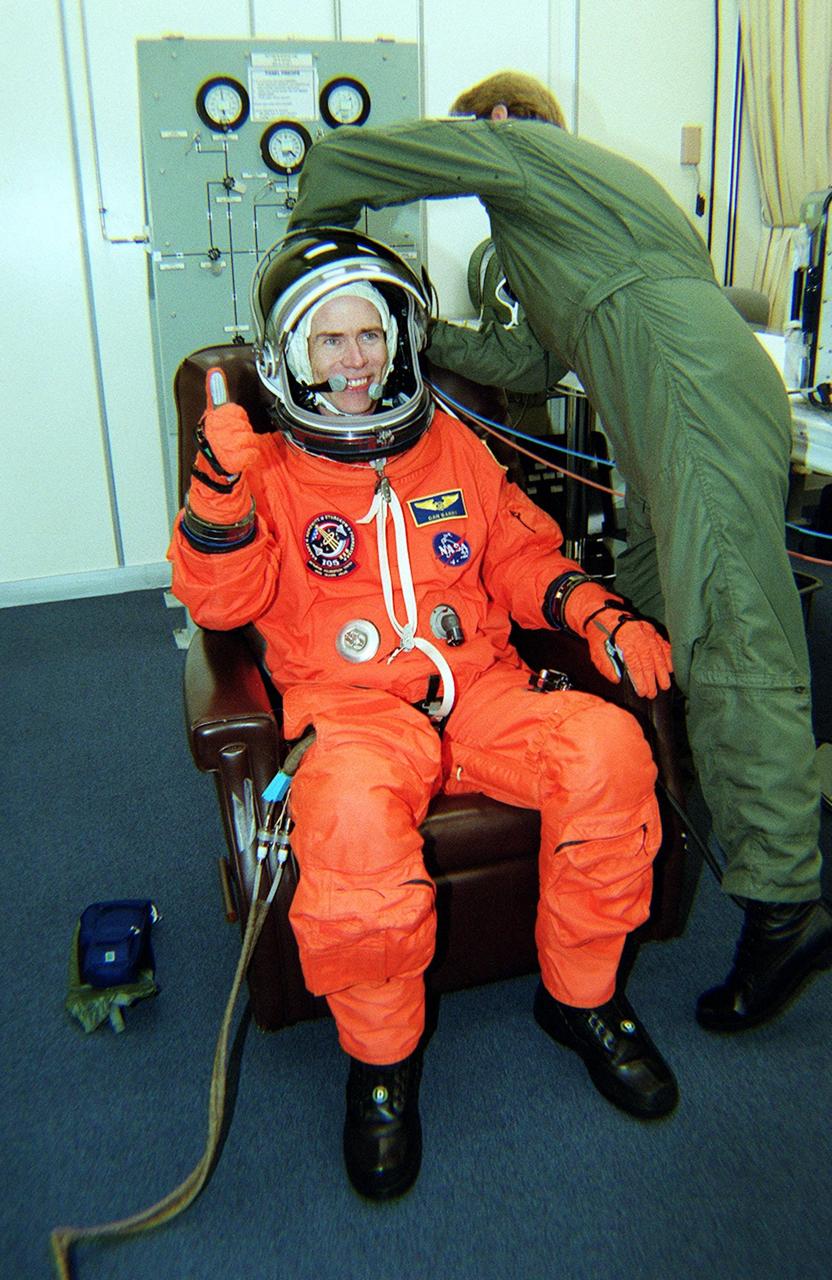 KENNEDY SPACE CENTER, Fla. -- STS-105 Mission Specialist Daniel Barry has his helmet checked during suitup. On the mission, Discovery will be transporting the Expedition Three crew and several scientific experiments and payloads to the ISS, including the Early Ammonia Servicer (EAS) tank. The EAS, which will support the thermal control subsystems until a permanent system is activated, will be attached to the Station during two spacewalks. The three-member Expedition Two crew will be returning to Earth aboard Discovery after a five-month stay on the Station. Launch is scheduled for 5:38 p.m. EDT Aug. 9