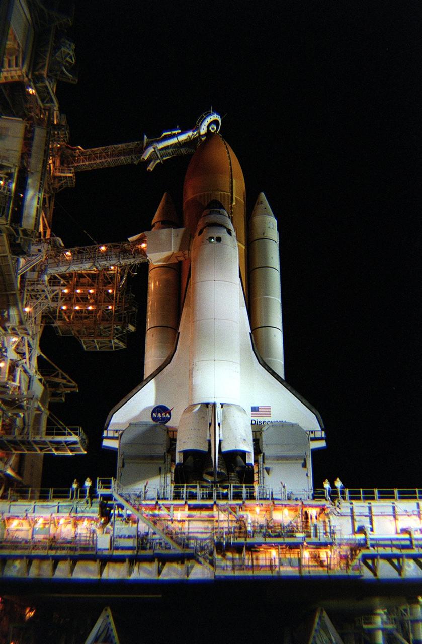 KENNEDY SPACE CENTER, Fla. -- Floodlights reveal the Space Shuttle Discovery after rollback of the Rotating Service Structure in preparation for launch on mission STS-105. Above the external tank, the “beanie cap” is poised, waiting for loading of the propellants. The cap, or vent hood, is on the end of the gaseous oxygen vent arm that allows gaseous oxygen vapors to vent away from the Space Shuttle. Below, on either side of the orbiter’s tail are the tail service masts that support the fluid, gas and electrical requirements of the orbiter’s liquid oxygen and liquid hydrogen aft T-0 umbilicals. On the mission, Discovery will be transporting the Expedition Three crew and several  scientific experiments and payloads to the International Space Station, including the Early Ammonia Servicer (EAS) tank. The EAS, which will support the thermal control subsystems until a permanent system is activated, will be attached to the Station during two spacewalks. The three-member Expedition Two crew will be returning to Earth aboard Discovery after a five-month stay on the Station. Launch is scheduled for 5:38 p.m. EDT Aug. 9