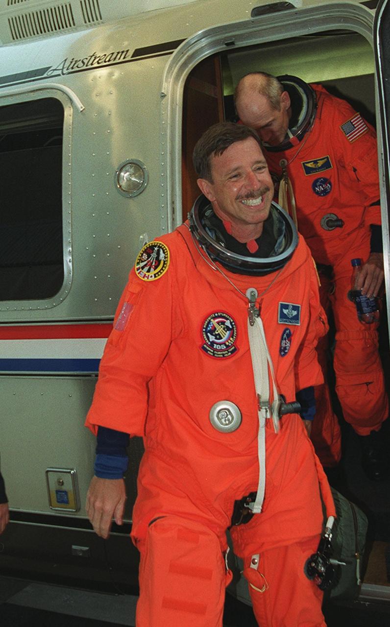 KENNEDY SPACE CENTER, Fla. -- After a 24-hour delay of the STS-105 launch, Commander Scott Horowitz is the first off the Astrovan returning the crews to the Operations and Checkout Building. Behind him is Mission Specialist Daniel Barry. Launch countdown activities for the 12-day mission were called off at about 5:12 p.m. Aug. 9 during the T-9 minute hold due to the high potential for lightning, a thick cloud cover and the potential for showers. These were clear violations of launch weather criteria. The next launch attempt will be on Friday, Aug. 10, at the preferred launch time of about 5:15 p.m. The launch window extends for about 5 minutes. On the mission, Space Shuttle Discovery will be transporting the Expedition Three crew and several scientific experiments and payloads to the International Space Station, including the Early Ammonia Servicer (EAS) tank. The EAS, which will support the thermal control subsystems until a permanent system is activated, will be attached to the Station during two spacewalks. The three-member Expedition Two crew will be returning to Earth aboard Discovery after a five-month stay on the Station