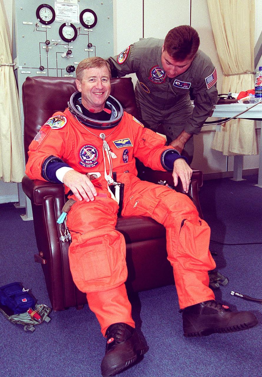 KENNEDY SPACE CENTER, Fla. -- Expedition Three Commander Frank Culbertson is helped with his launch and entry suit for the second launch attempt after a 24-hour weather delay. Launch countdown activities for the 12-day mission were called off at about 5:12 p.m. Aug. 9 during the T-9 minute hold due to the high potential for lightning, a thick cloud cover and the potential for showers. Launch is currently scheduled for 5:15 p.m. EDT Aug. 10. Highlighting the mission will be the rotation of the International Space Station crew, the third flight of an Italian-built Multi-Purpose Logistics Module delivering additional scientific racks, equipment and supplies for the Space Station, and two spacewalks. Included in the payload is the Early Ammonia Servicer (EAS) tank, which will be attached to the Station during the spacewalks. The EAS will be installed on the P6 truss, which holds the Station’s giant U.S. solar arrays, batteries and the cooling radiators. The EAS contains spare ammonia for the Station’s cooling system. The three-member Expedition Two crew will be returning to Earth aboard Discovery after a five-month stay on the Station