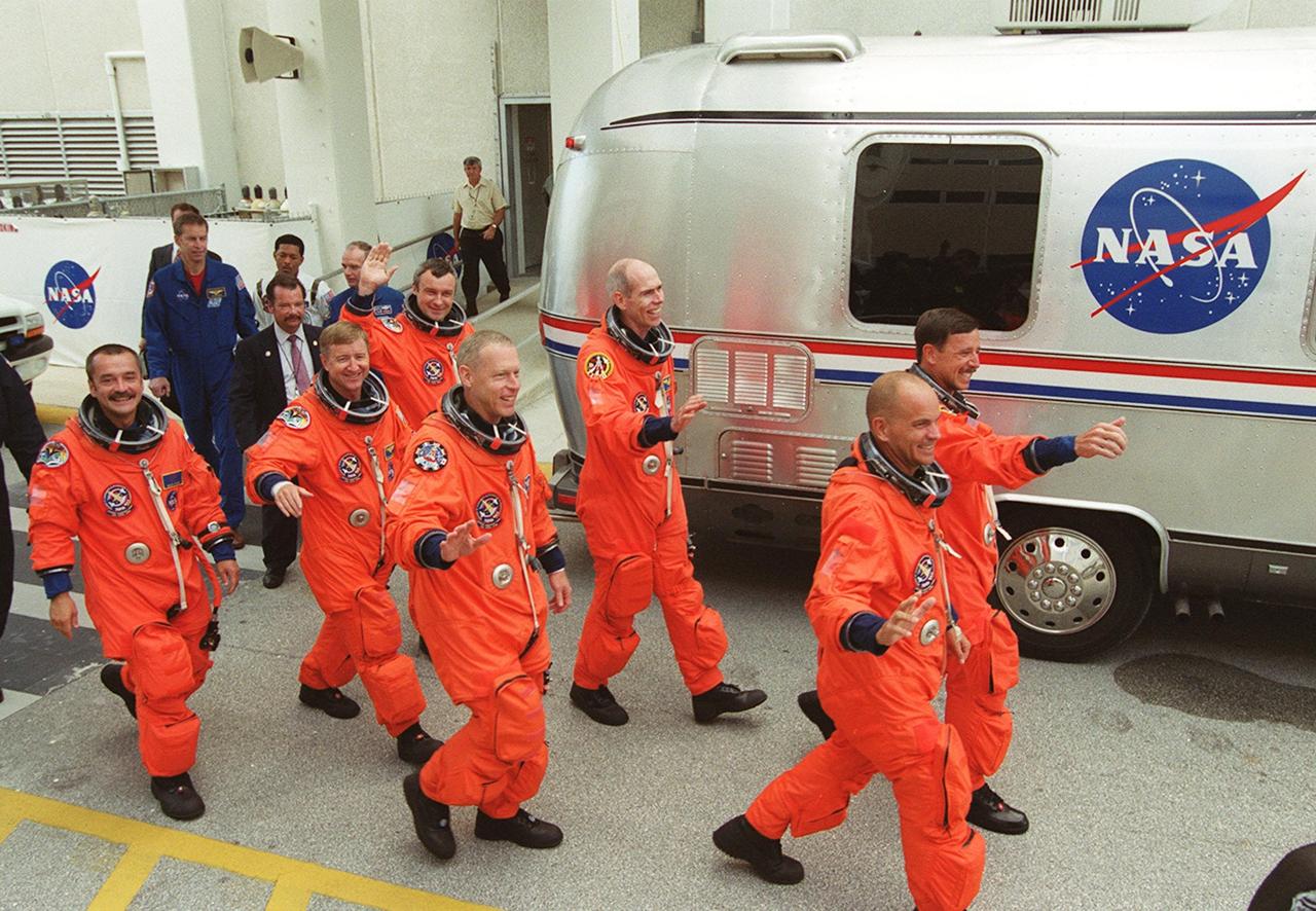 KENNEDY SPACE CENTER, Fla. -- Waving to onlookers, the STS-105 and Expedition Three (E3) crews head to the Astrovan that will take them to Launch Pad 39A for a second attempt at launch on mission STS-105. From the left are E3 cosmonaut Mikhail Tyurin, Commander Frank Culbertson and cosmonaut Vladimir Dezhurov; STS-105 Mission Specialists Patrick Forrester and Daniel Barry, Pilot Rick Sturckow and Commander Scott Horowitz. . Launch countdown activities for the 12-day mission were called off at about 5:12 p.m. Aug. 9 during the T-9 minute hold due to the high potential for lightning, a thick cloud cover and the potential for showers. Launch is currently scheduled for 5:15 p.m. EDT Aug. 10. Highlighting the mission will be the rotation of the International Space Station crew, the third flight of an Italian-built Multi-Purpose Logistics Module delivering additional scientific racks, equipment and supplies for the Space Station, and two spacewalks. Included in the payload is the Early Ammonia Servicer (EAS) tank, which will be attached to the Station during the spacewalks. The EAS will be installed on the P6 truss, which holds the Station’s giant U.S. solar arrays, batteries and the cooling radiators. The EAS contains spare ammonia for the Station’s cooling system. The three-member Expedition Two crew will be returning to Earth aboard Discovery after a five-month stay on the Station